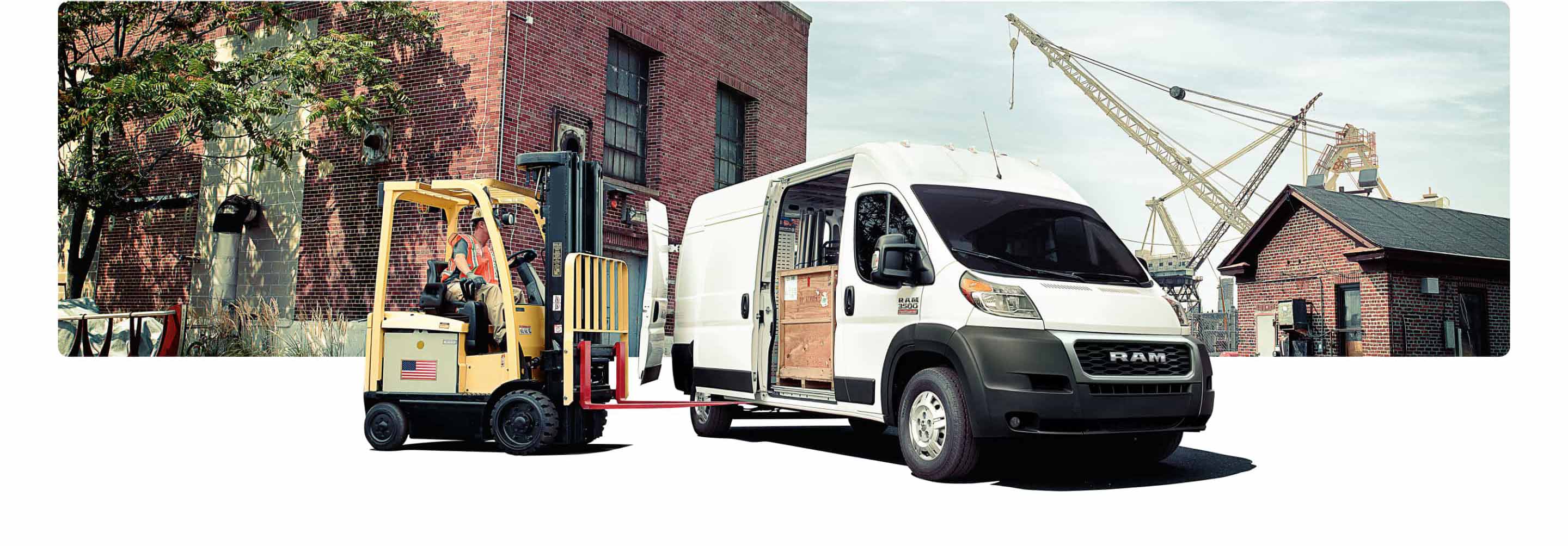 La Ram ProMaster 2021 estacionada frente a un almacén con un montacargas que se acerca a su puerta lateral abierta para descargar las cajas que tiene adentro.