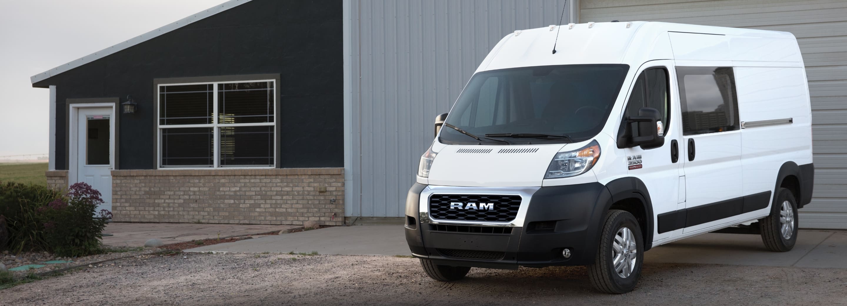 Una cargo van Ram ProMaster 3500 2021 blanca estacionada afuera de un edificio comercial.