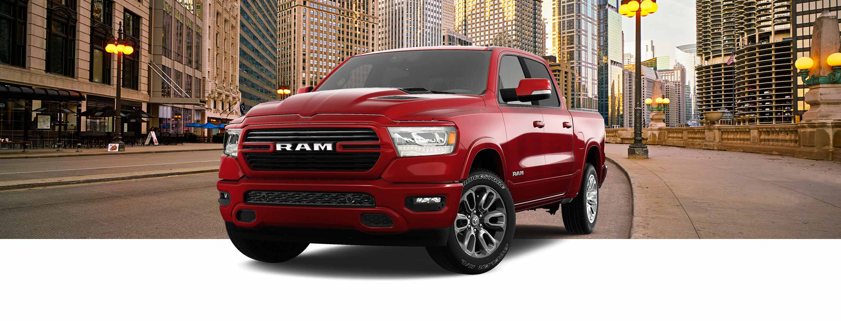 Una Ram 1500 Laramie Crew Cab 2023 roja con el paquete de apariencia deportiva, con una calle urbana metropolitana de fondo.