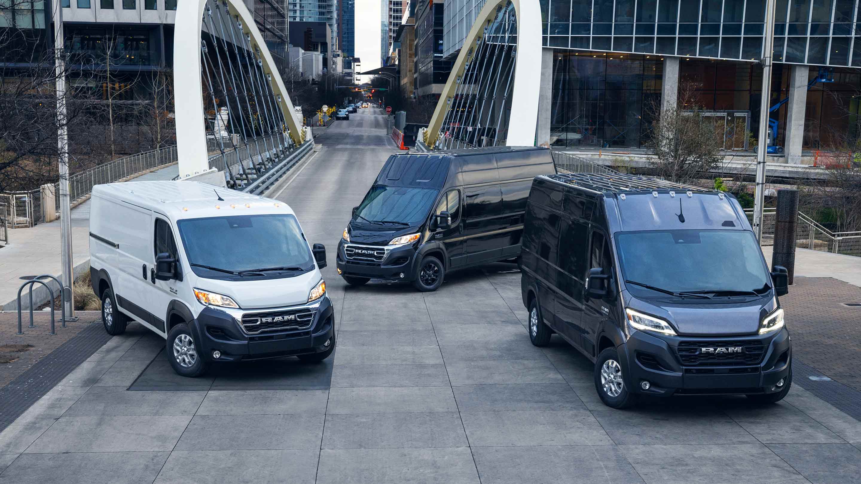 Tres vans Ram ProMaster 2023 estacionadas en una calle urbana: una Cargo Van 1500, una Cargo Van Super High Roof 3500 y una Cargo Van High Roof 2500/3500.