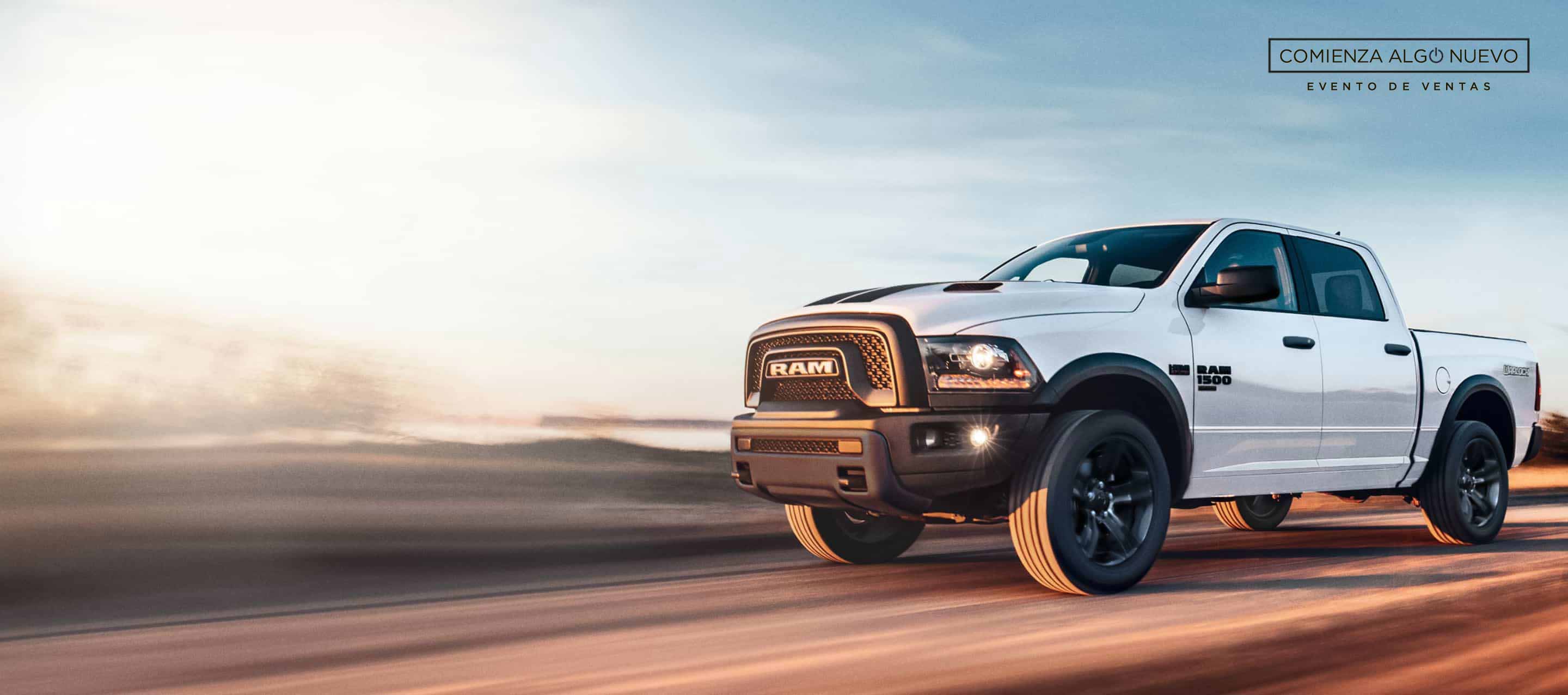 Una Ram 1500 Classic Warlock 4x4 Crew Cab 2024 blanca circulando por una carretera. El evento de ventas “Comienza algo nuevo”.