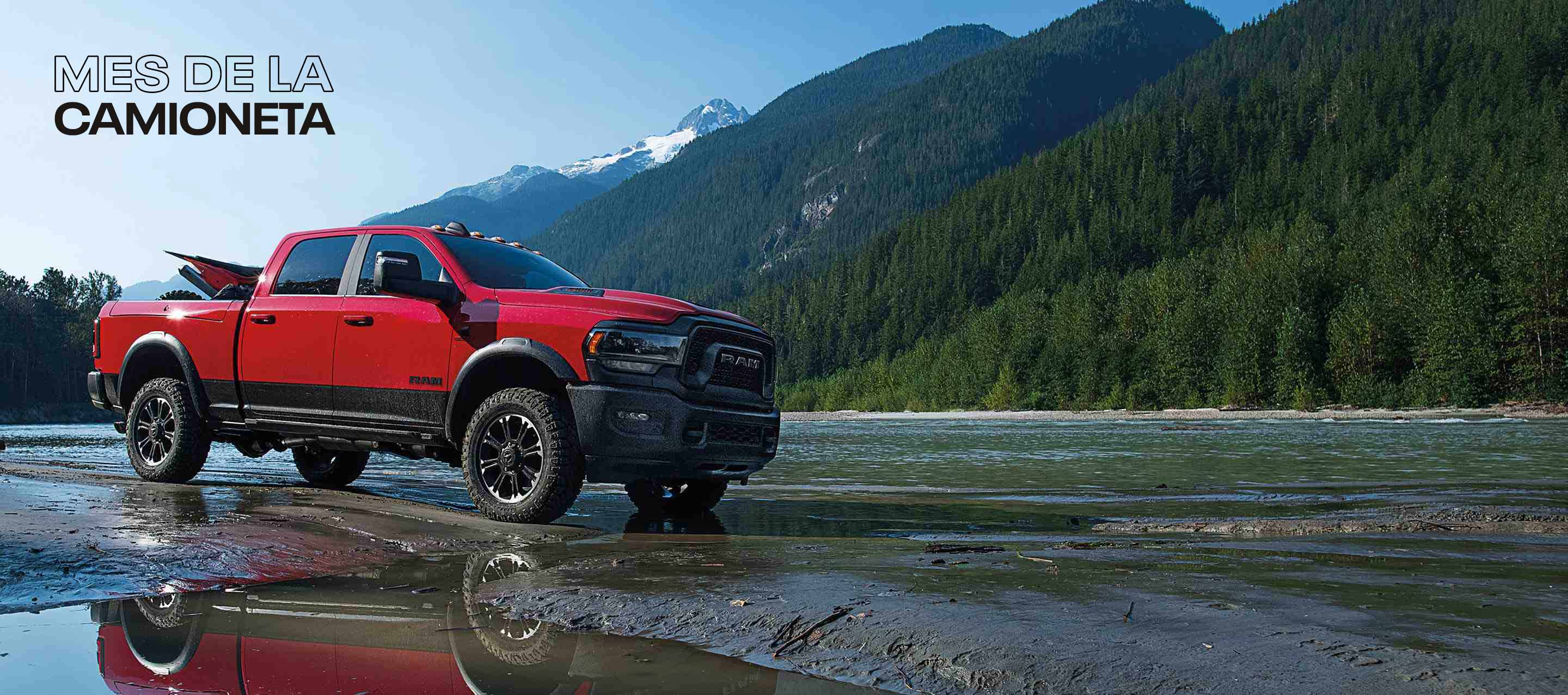 Una Ram 2500 Rebel 4x4 Crew Cab 2024 roja con un ATV en su plataforma, con montañas de fondo. Mes de las camionetas.