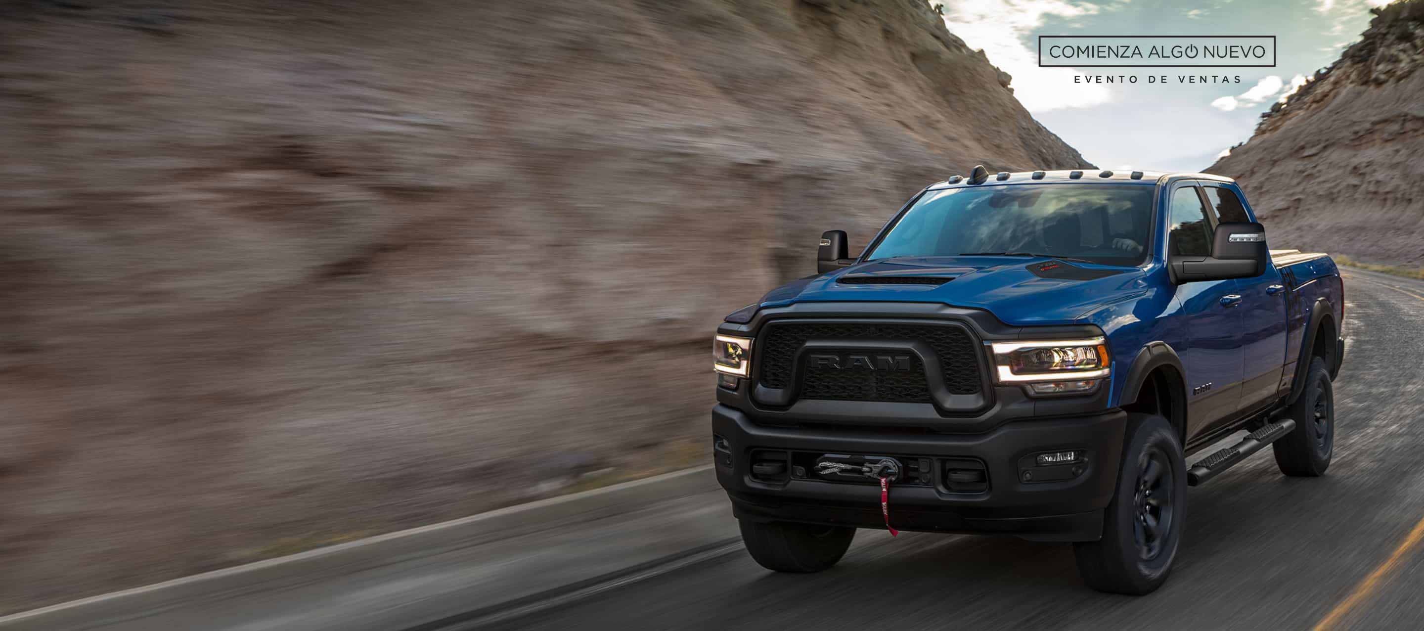 Una Ram 2500 Power Wagon Crew Cab 2024 azul encarando una curva en una carretera de montaña. El evento de ventas “Comienza algo nuevo”.