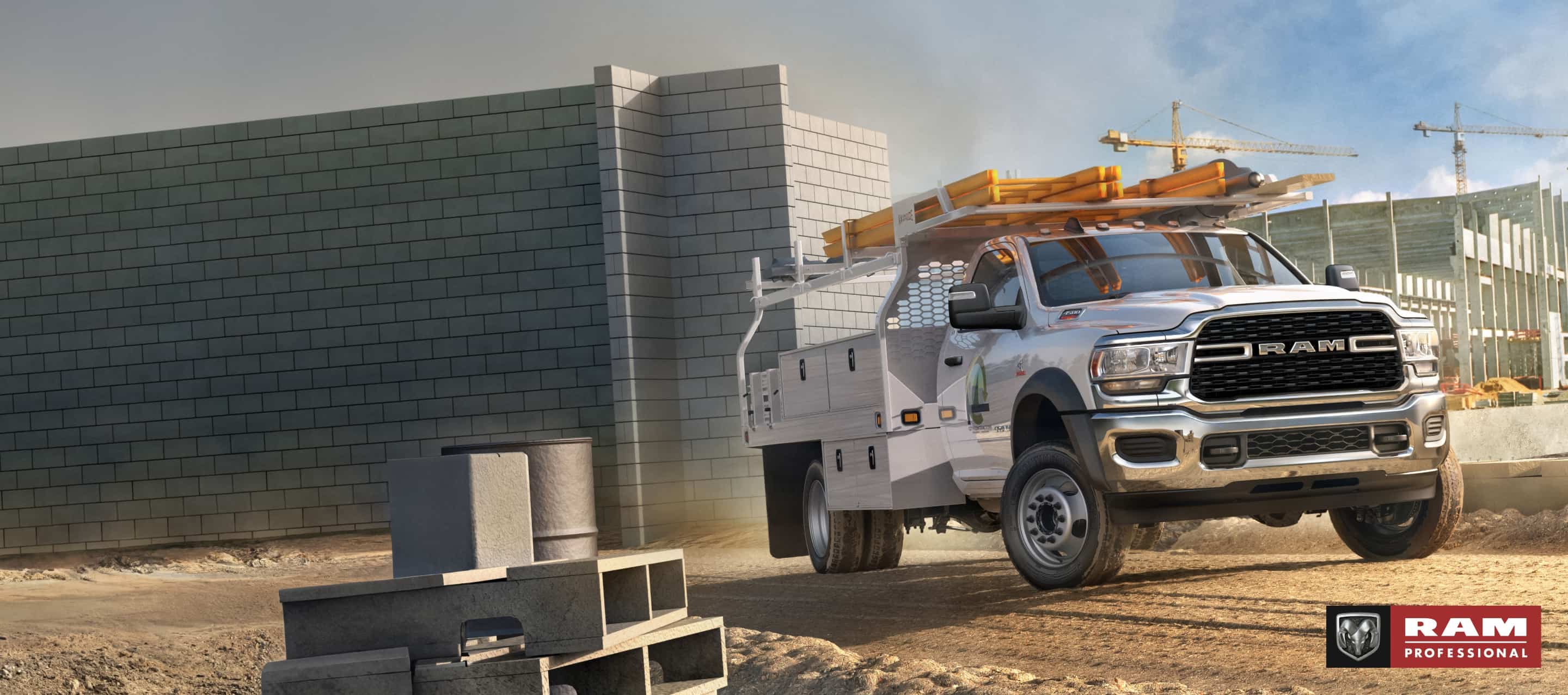 Una Ram 4500 Chassis Cab Regular Cab 2024 blanca con una mejora utilitaria, estacionada en una obra de construcción comercial grande. Ram Professional.