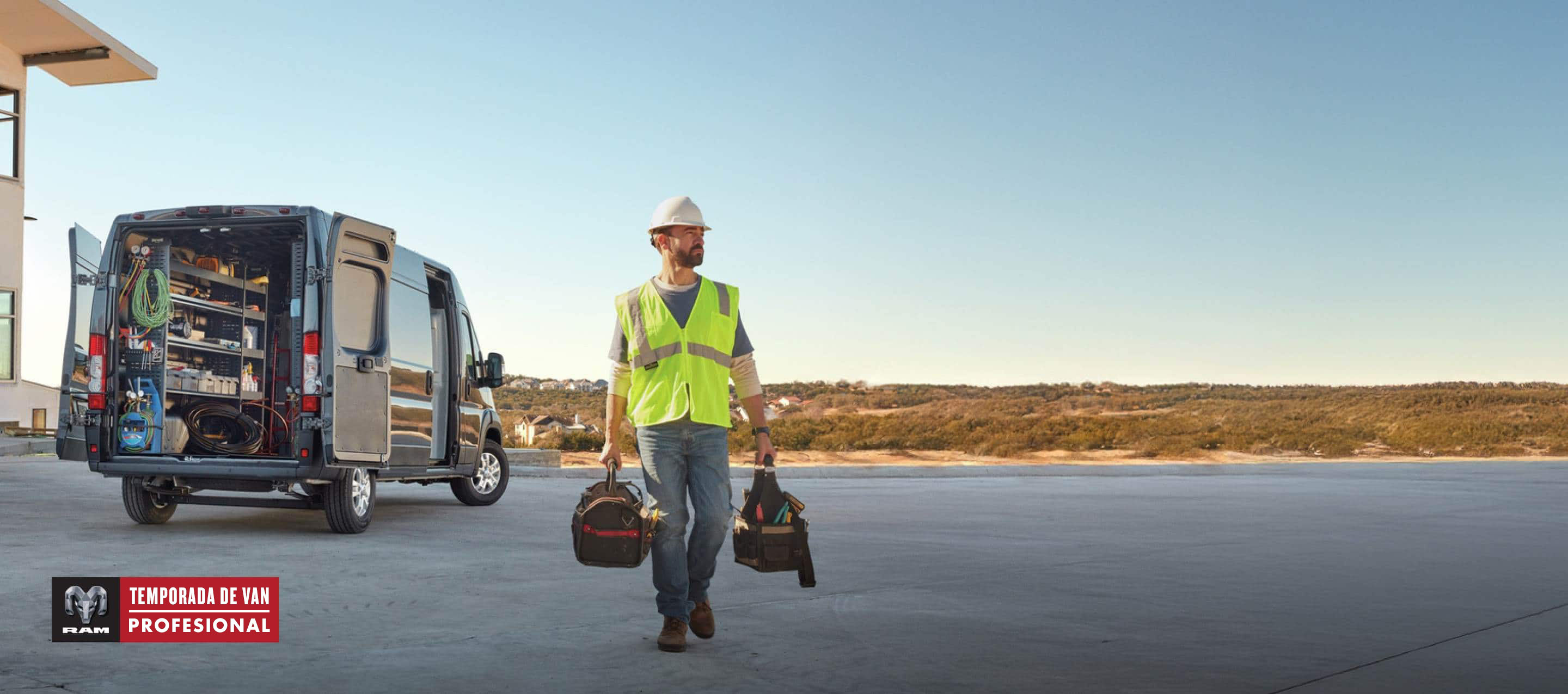 La parte trasera de una Ram ProMaster 3500 SLT Plus High Roof Cargo Van 2024 gris con la puerta corrediza del lado del pasajero y las puertas traseras abiertas, para exhibir estanterías llenas de herramientas y un técnico alejándose del vehículo. Evento de ventas Temporada de vans profesionales.