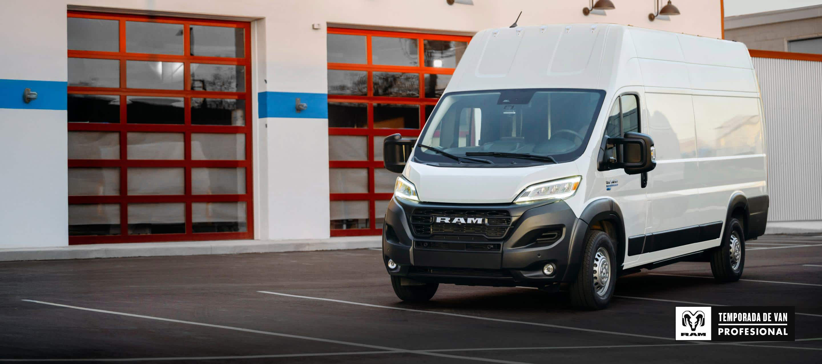 Ángulo delantero del lado del pasajero de una van Ram ProMaster EV 3500 Super High Roof Step 2024 blanca estacionada cerca de un garaje comercial. Temporada de vans profesionales Ram.