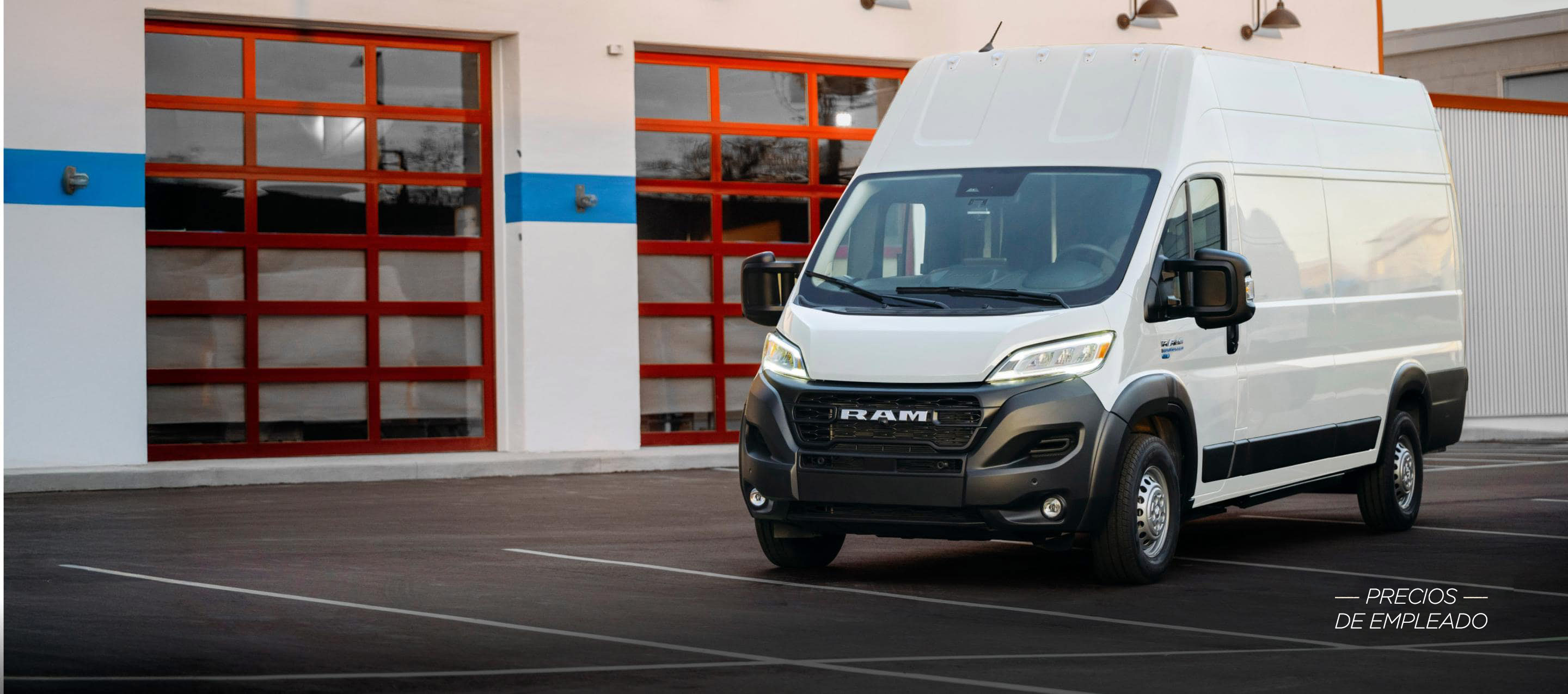 Ángulo delantero del lado del pasajero de una van Ram ProMaster EV 3500 Super High Roof Step 2024 blanca estacionada cerca de un garaje comercial. Evento de ventas Precios de empleado.