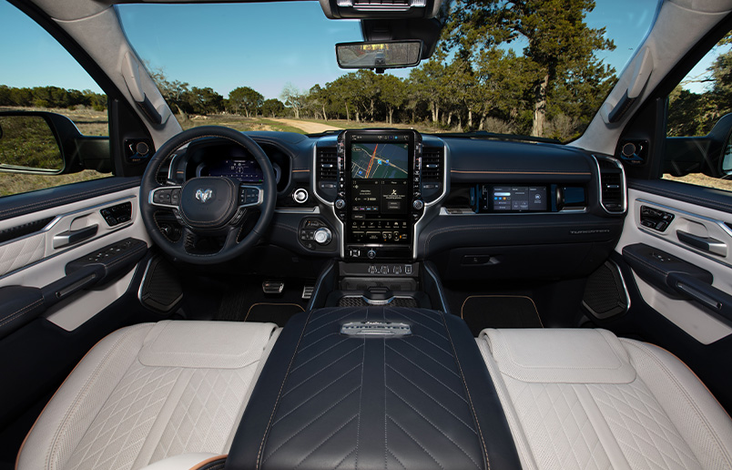 El volante, la pantalla digital en el panel de instrumentos, la pantalla táctil Uconnect y la pantalla táctil interactiva para el pasajero delantero en la Ram 1500 Tungsten 2025.