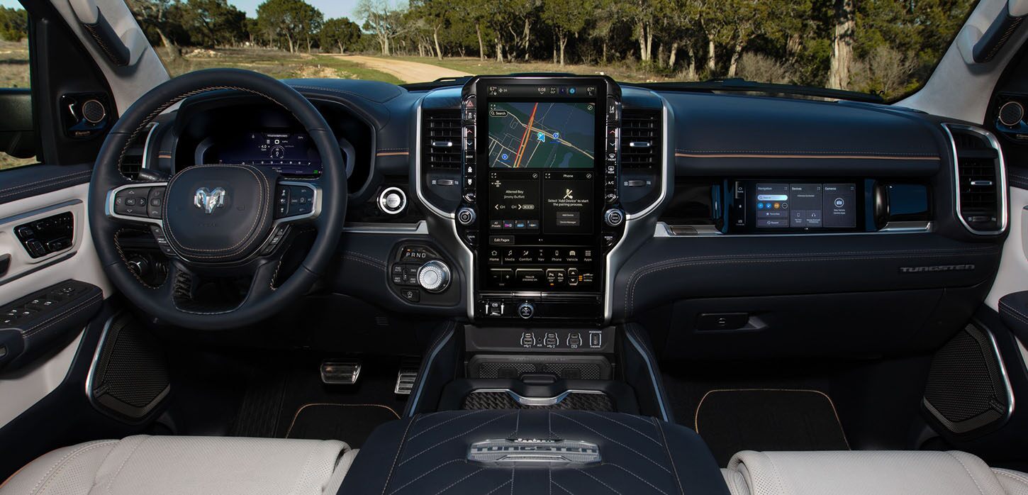 El volante, la pantalla digital de información para el conductor en el panel de instrumentos, la pantalla táctil de Uconnect y la pantalla táctil interactiva para el pasajero delantero en la Ram 1500 Tungsten 2025.