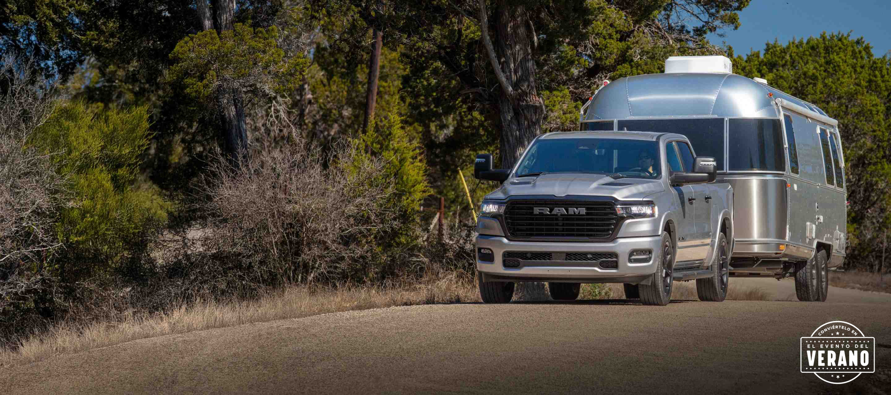 Una Ram 1500 Tungsten Crew Cab 2025 plateada circulando por un puente de una autopista en una ciudad con edificios altos de fondo. Conviértelo en el evento del verano.