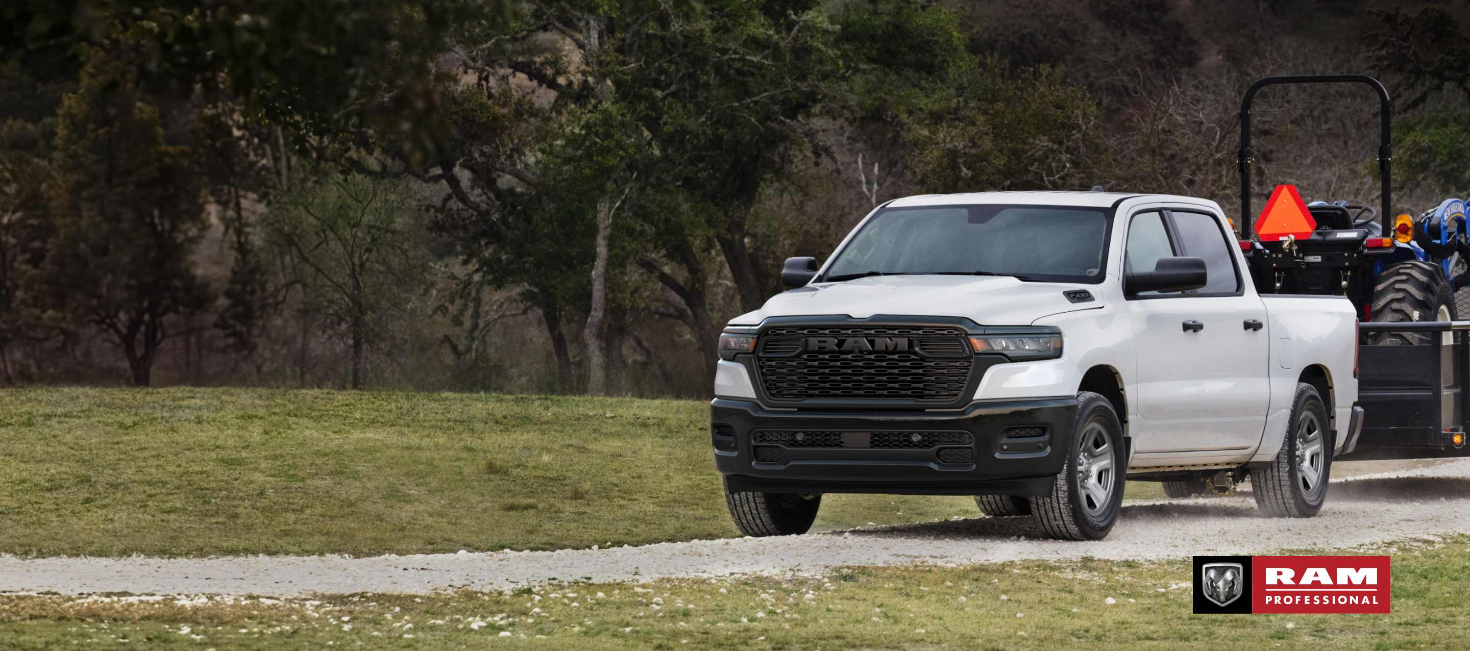 Una Ram 1500 Tradesman 4x4 Crew Cab 2025 blanca remolcando un tractor. Ram Professional.