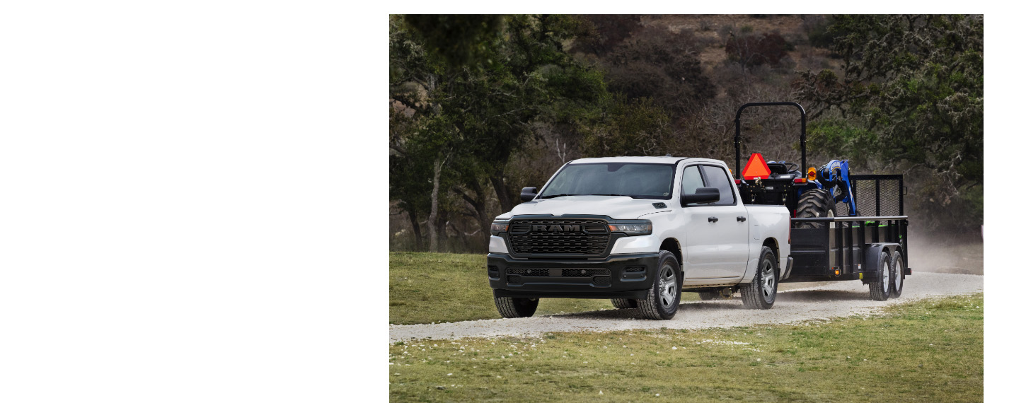 Una Ram 1500 Tradesman 4x4 Crew Cab 2025 blanca remolcando un tractor.