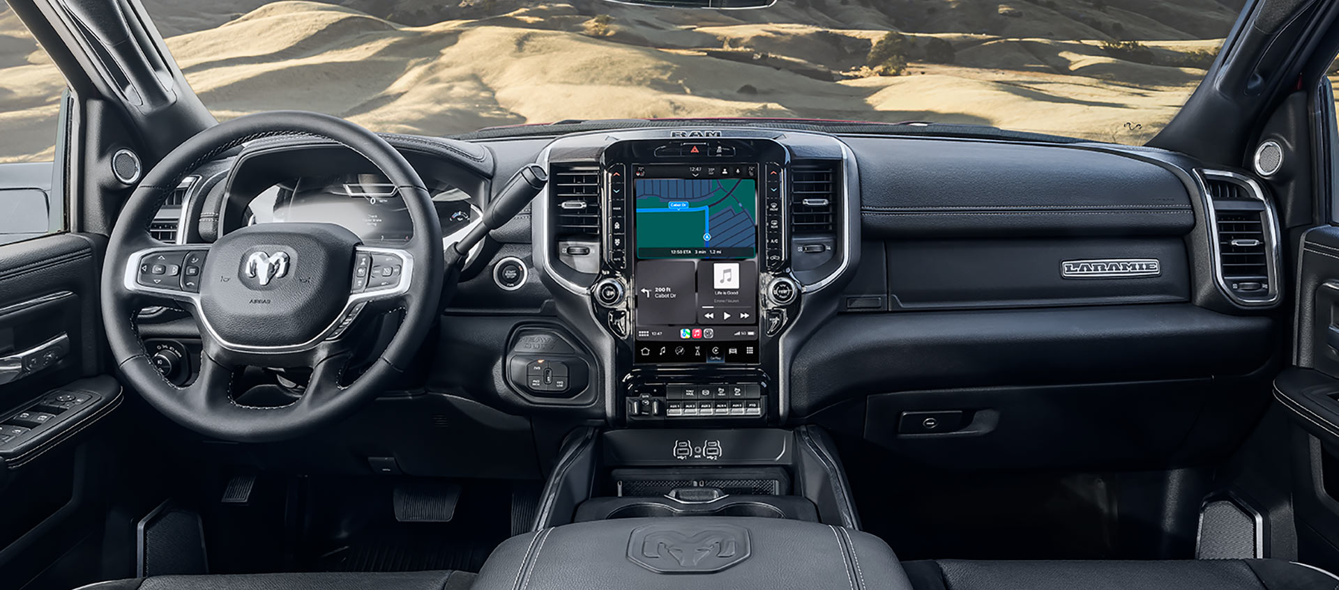 El interior de una Ram 2500 Laramie 2025 desde la perspectiva del conductor, en la que se muestra a través del parabrisas que el vehículo está en el desierto.