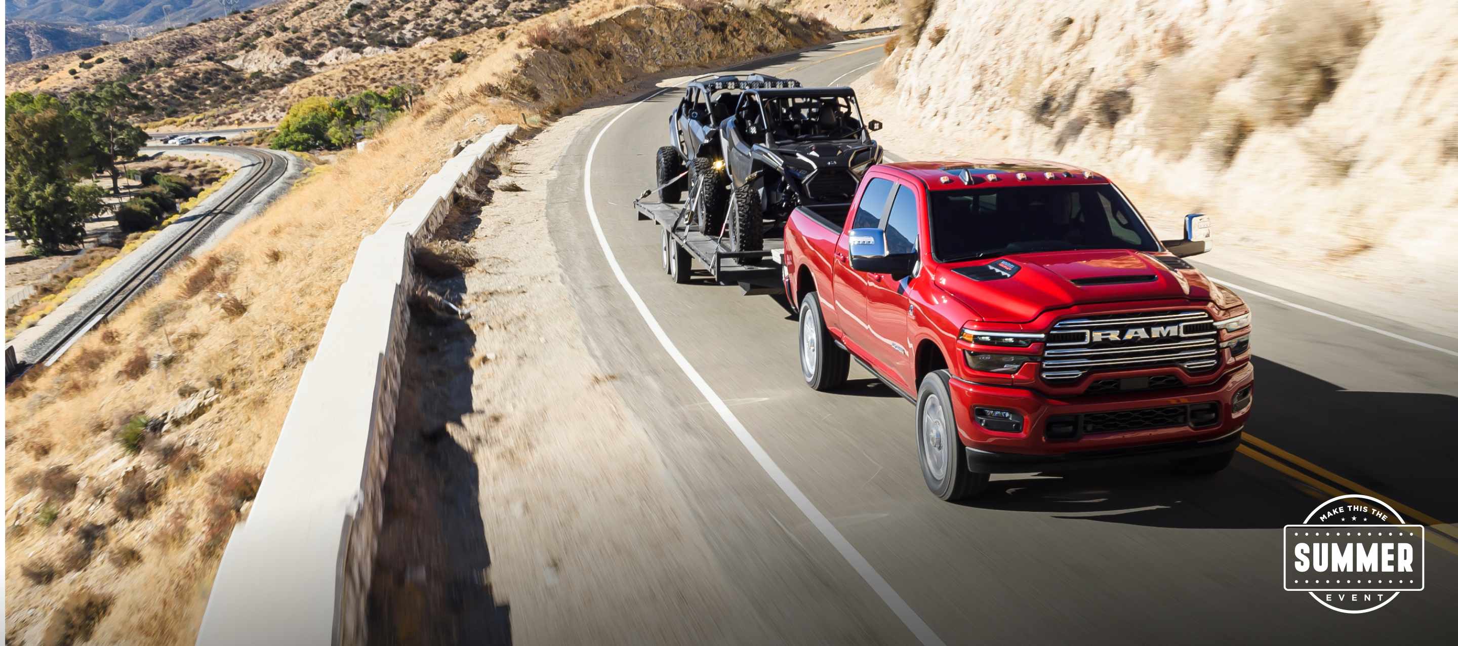 Una Ram 2500 Laramie 4x4 Crew Cab 2025 roja circulando por una carretera en las montañas, mientras remolca dos ATV. Conviértelo en el evento del verano.