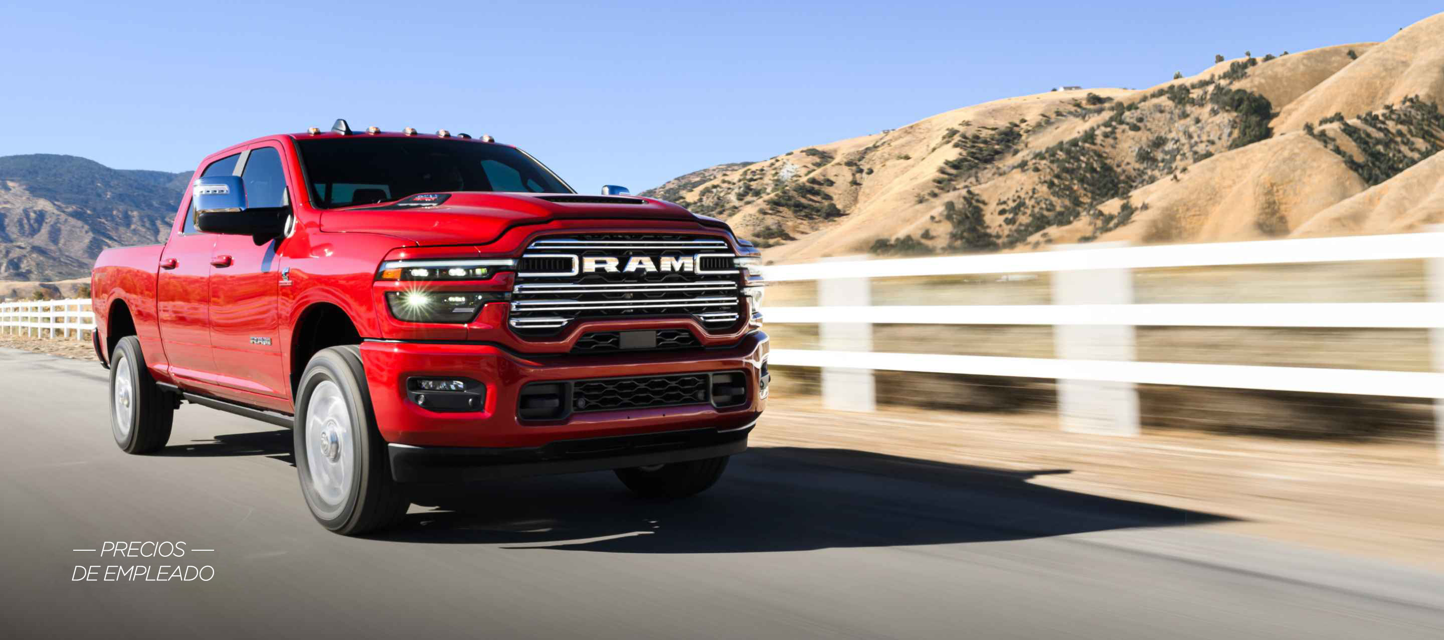 Una Ram 2500 Laramie 4x4 Crew Cab 2025 roja circulando por una carretera, con montañas de fondo. Evento de ventas Precios de empleado.