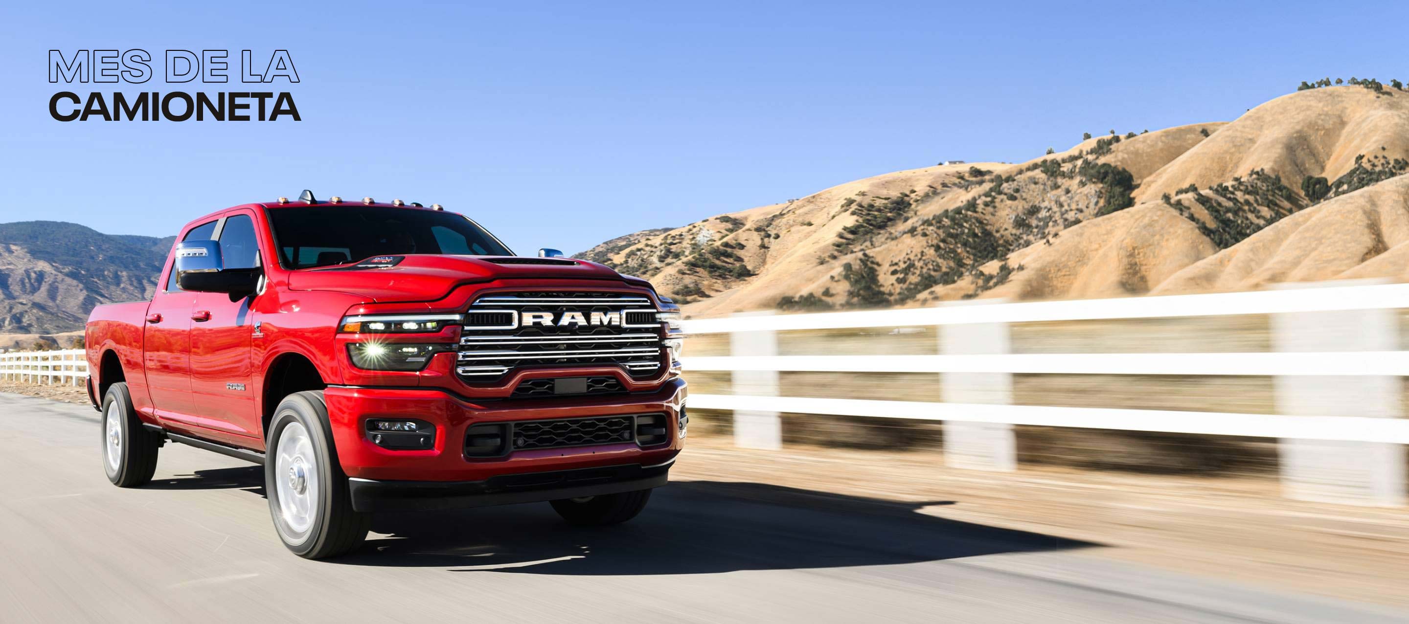 Una Ram 2500 Laramie 4x4 Crew Cab 2025 roja circulando por una carretera, con montañas de fondo. Mes de las camionetas.