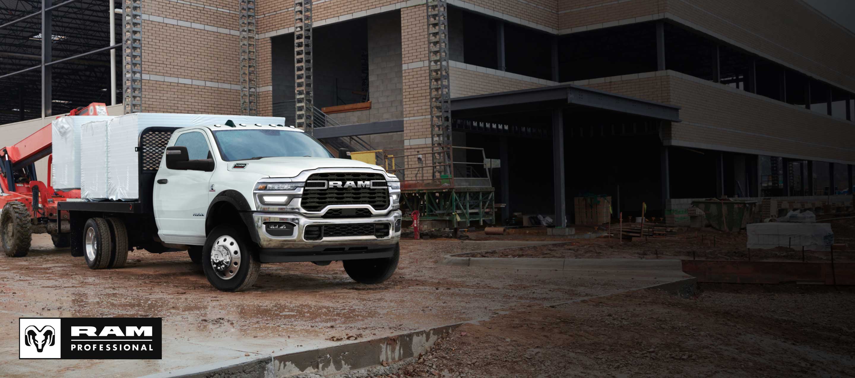 Una Ram 3500 Big Horn 4x4 Chassis Cab Regular Cab 2025 blanca con una mejora de plataforma cargada con materiales de construcción, estacionada en una obra de construcción comercial. Ram Professional.