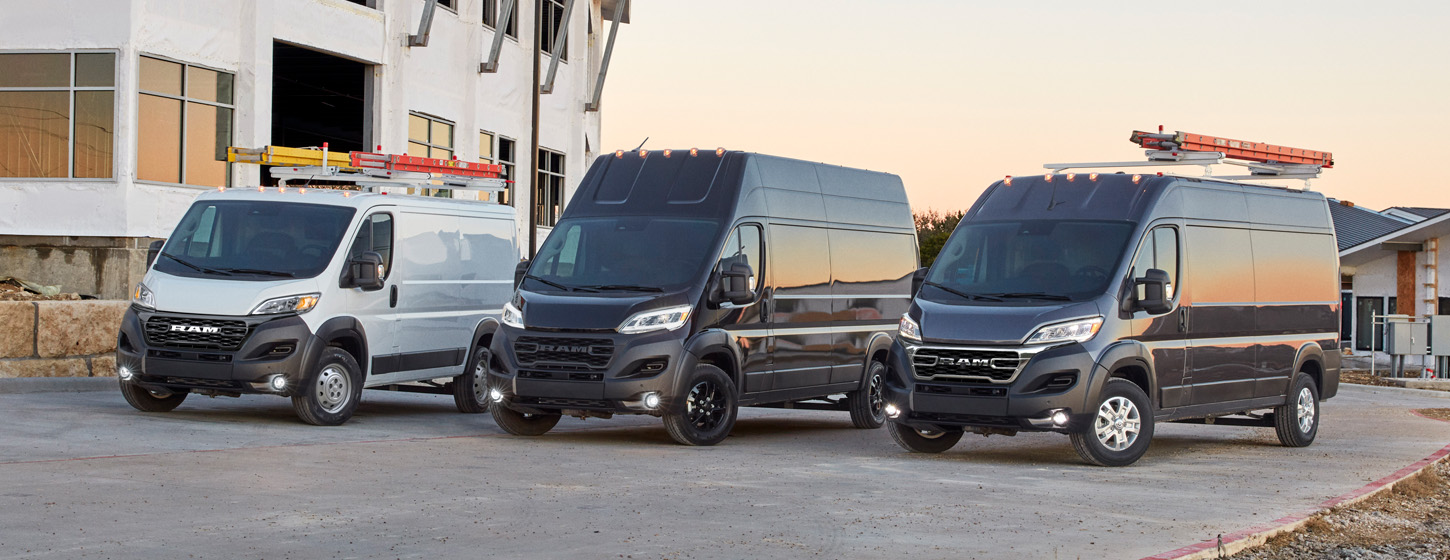 Una línea de tres vans Ram ProMaster 2025, cada una con distinta altura de techo, estacionadas en una obra de construcción; de izquierda a derecha, una Ram ProMaster 1500 Tradesman Cargo Van Standard Roof blanca, una Ram ProMaster 3500 SLT Plus Cargo Van Super High Roof negra y una Ram ProMaster 2500 SLT Cargo Van High Roof negra.