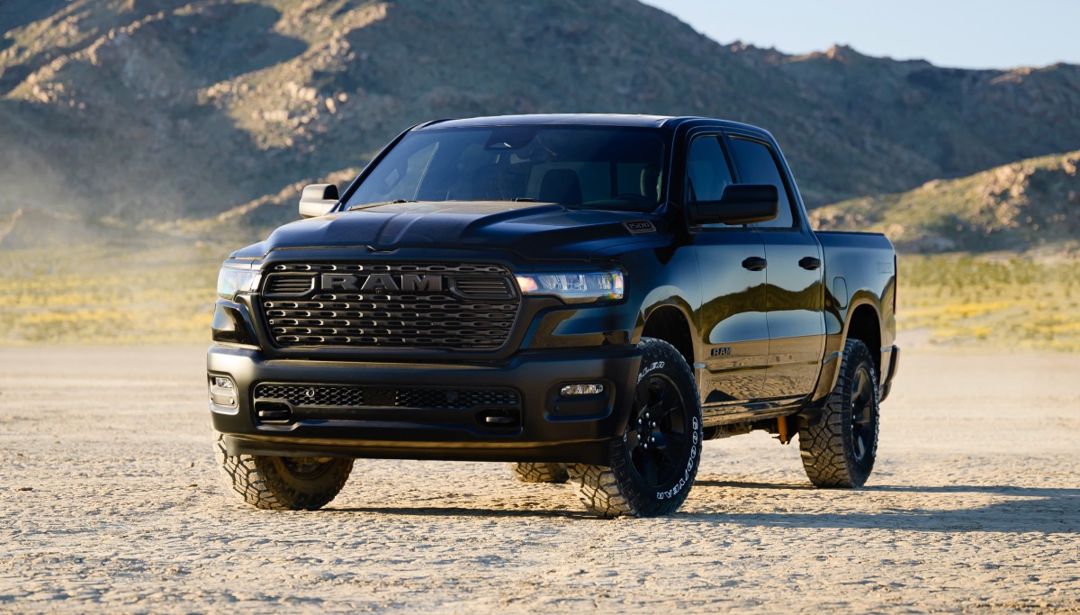 Se muestra una Ram 1500 Warlock 4x4 Crew Cab 2026 negra estacionada en el desierto, con montañas de fondo.