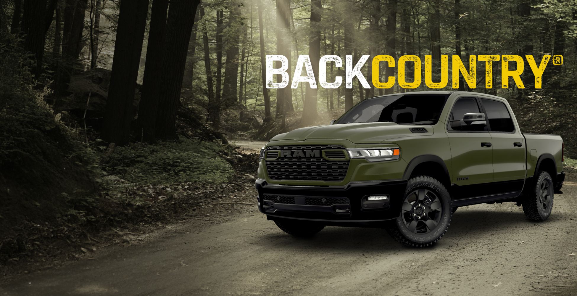 A driver-side front angle of a green Ram 1500 BackCountry 4x4 Crew Cab traveling on a dirt road in a forest. BackCountry.