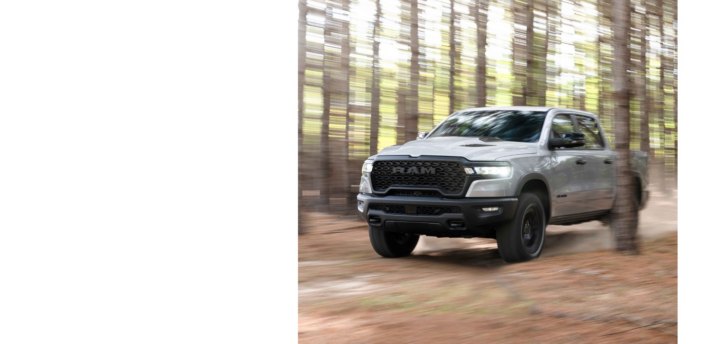 Una Ram 1500 Rebel 4x4 Crew Cab 2026 blanca circulando por un bosque con un fondo difuminado.