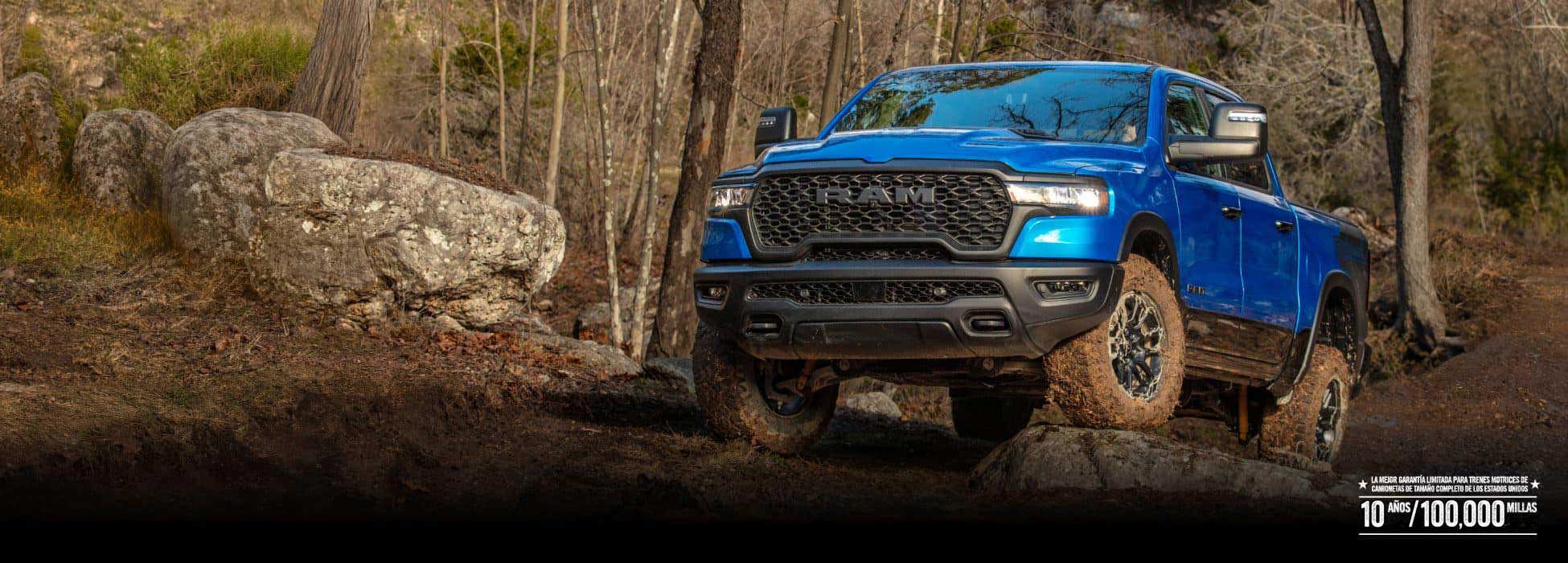 Una Ram 1500 Rebel 4x4 Crew Cab 2026 trepando por un terreno rocoso todoterreno con un bosque de fondo.