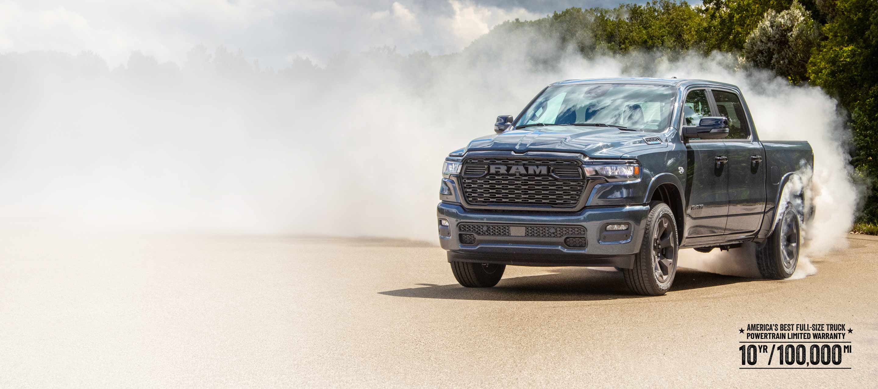 A passenger-side front angle of a blue 2026 Ram 1500 Big Horn 4x4 Crew Cab, with a trail of white smoke billowing from its rear tires. America's Best Full-Size Truck Powertrain Limited Warranty—10 Years/100,000 Miles.