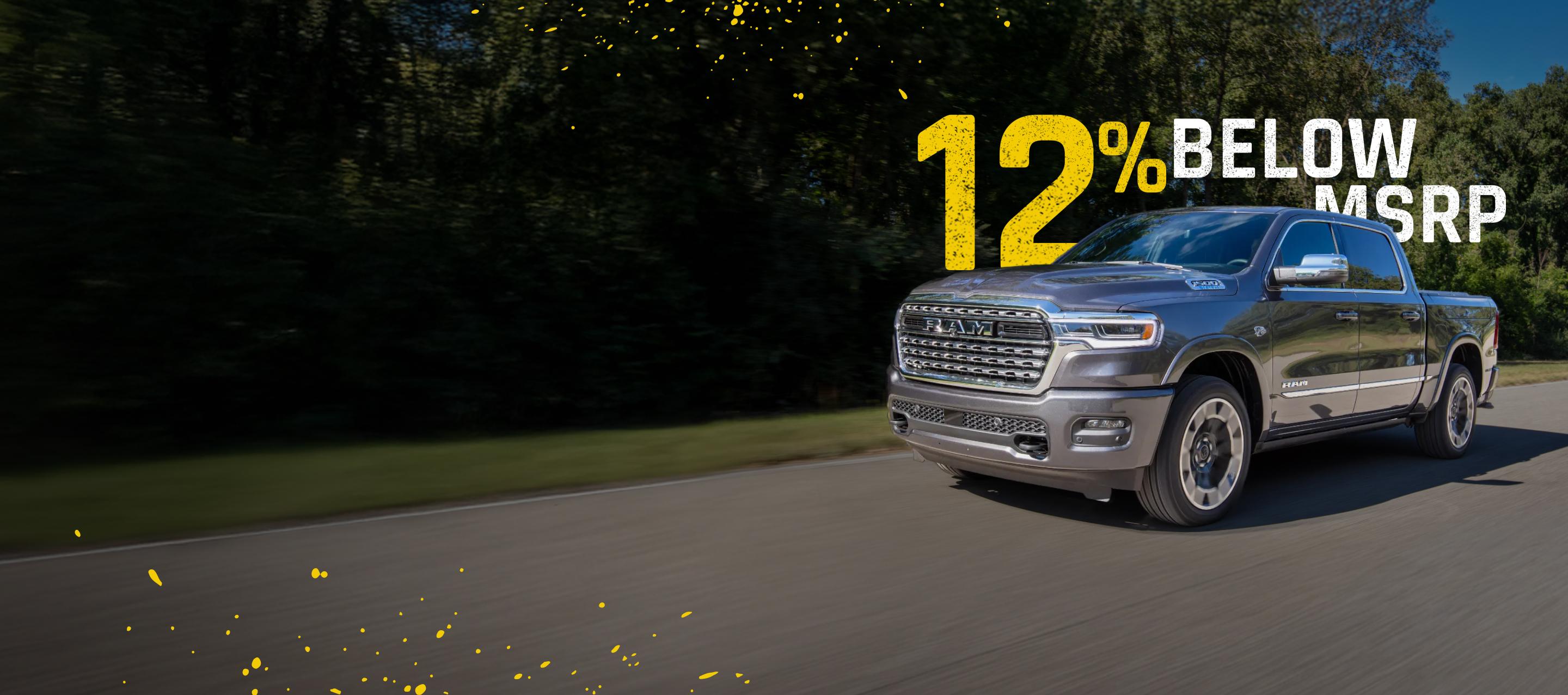 A gray 2026 Ram 1500 Limited 4x4 Crew Cab traveling down a country road. 12% below MSRP.