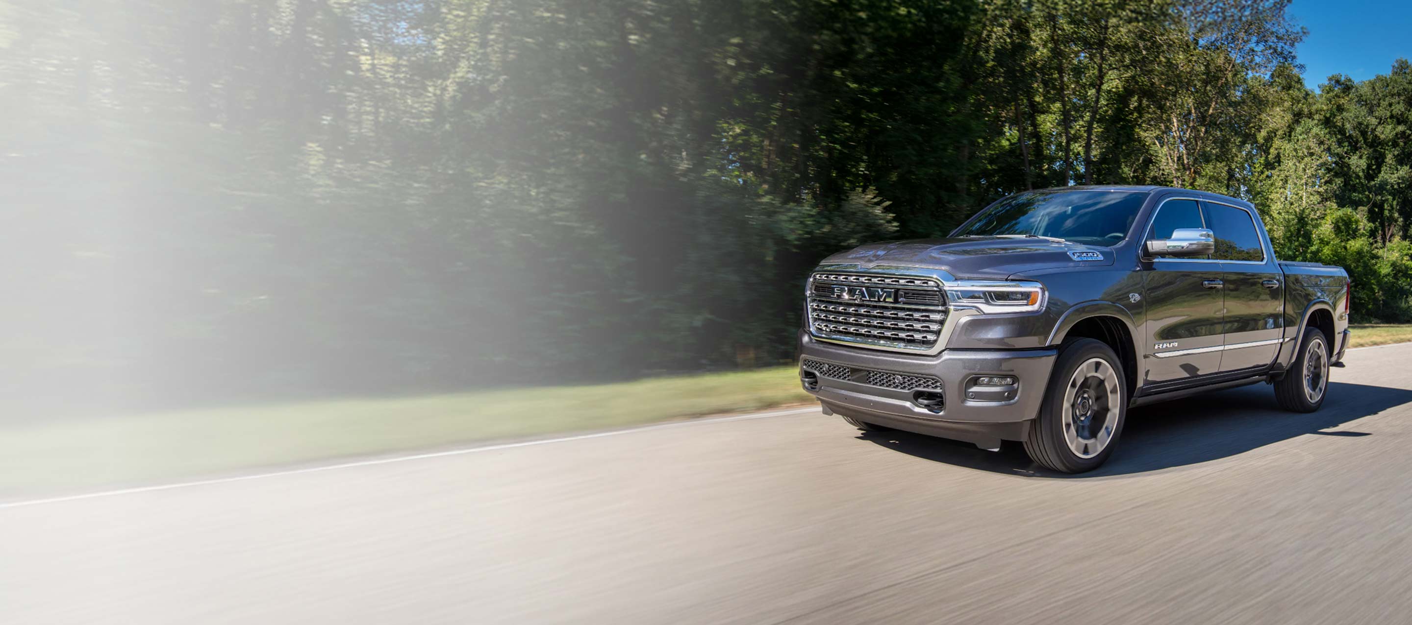 Una Ram 1500 Limited 4x4 Crew Cab 2026 gris circulando por un camino campestre. Evento de ventas Drive Into Fall y 10 AÑOS/100000 millas.