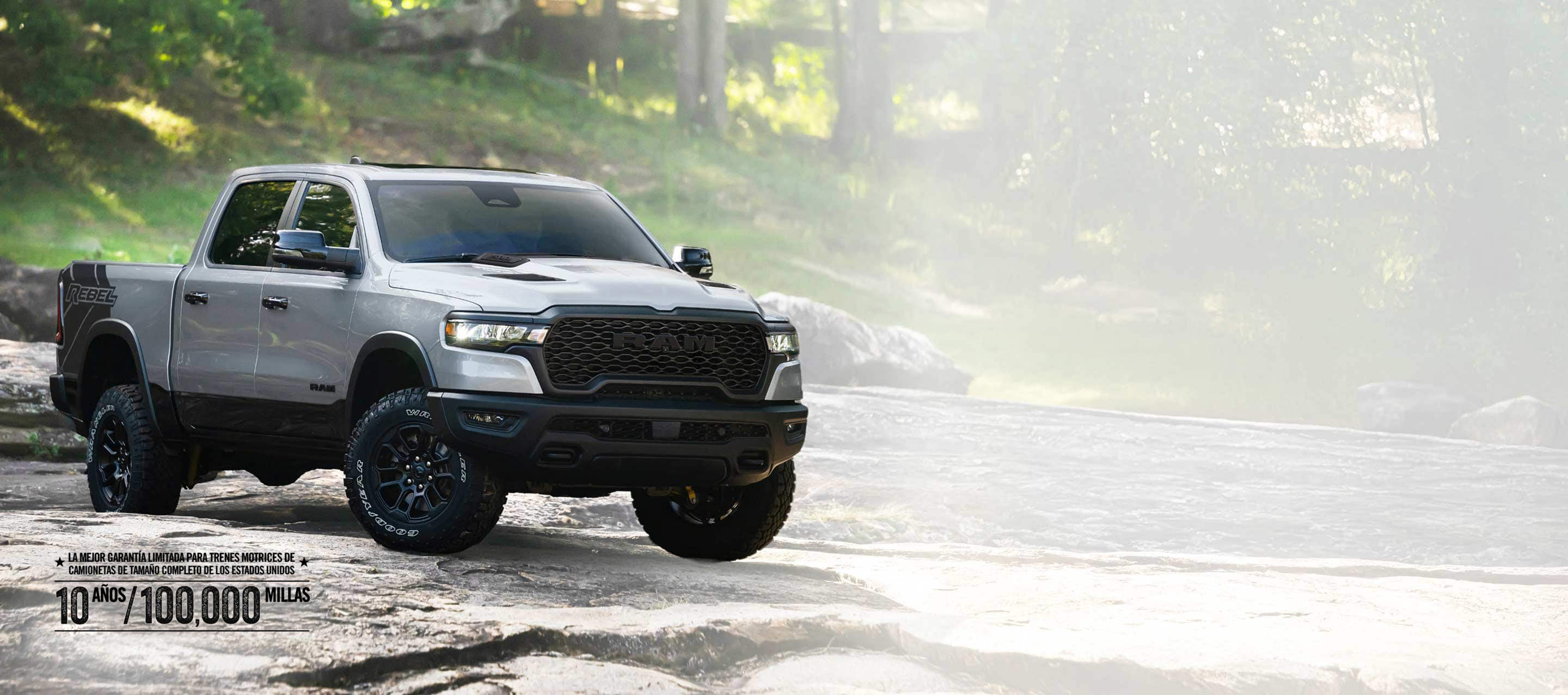 Una Ram 1500 Rebel 4x4 Crew Cab 2026 plateada recorriendo un sendero irregular fuera de carretera. La mejor garantía limitada del tren motriz para camionetas de tamaño completo de los Estados Unidos, de 10 años/100,000 millas.