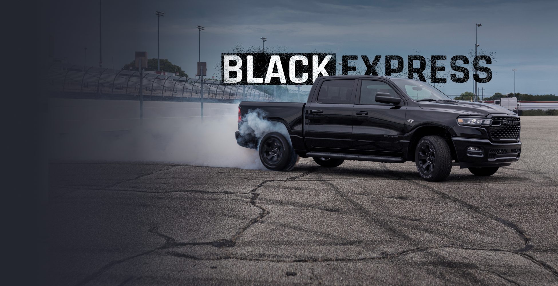 Perfil del lado del pasajero en ángulo de una Ram 1500 Black Express Crew Cab 2026 en una pista de carreras, despidiendo humo de sus neumáticos traseros. Black Express.
