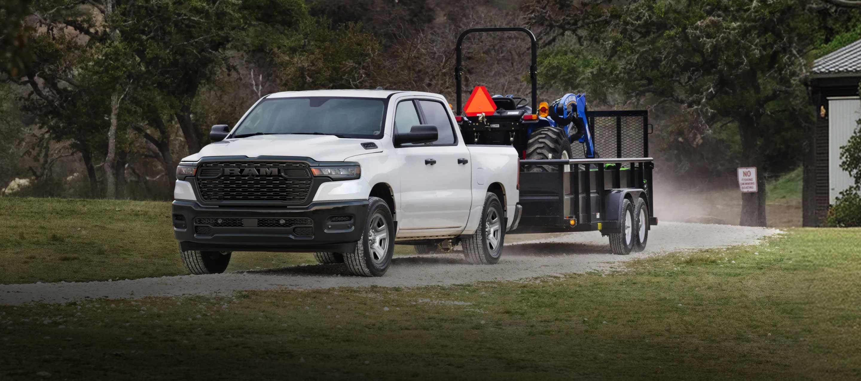 Una Ram 1500 Tradesman 4x4 Crew Cab 2026 blanca remolcando un tractor.