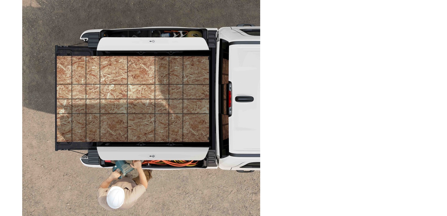 Ángulo aéreo de la caja de una camioneta Ram 1500 2026 llena con láminas de madera contrachapada.