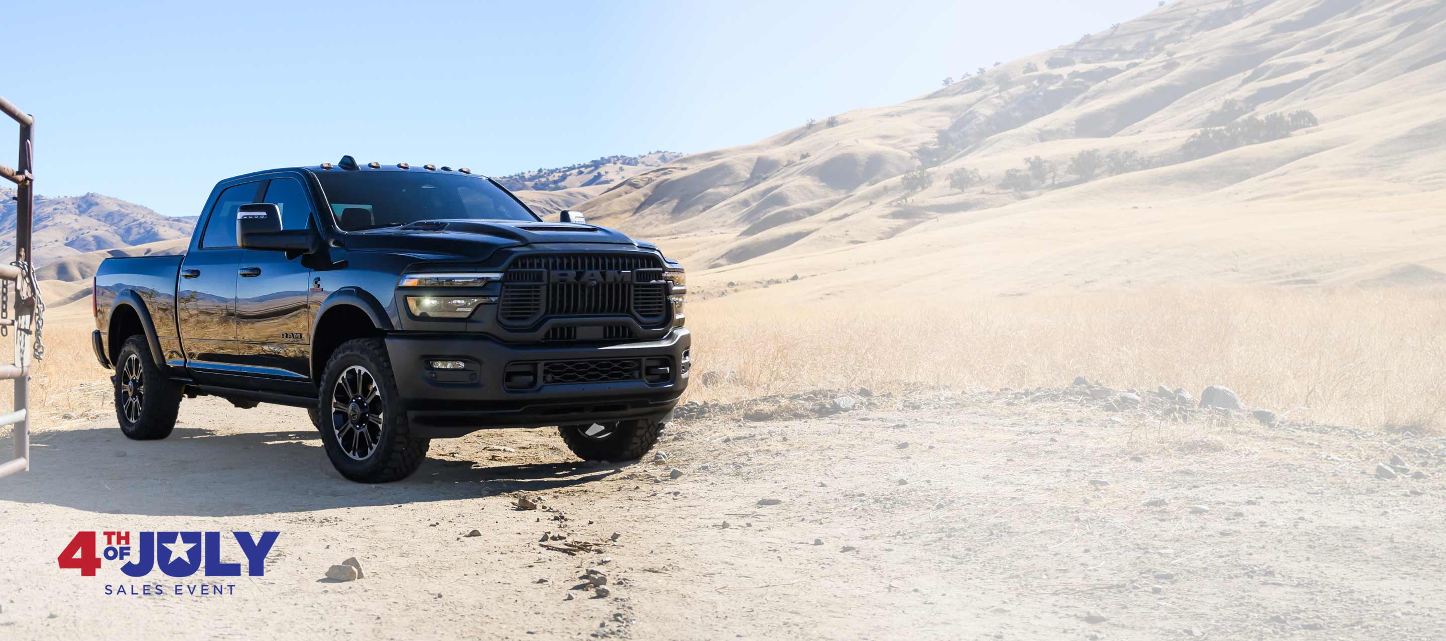 Una Ram 2500 Rebel 4x4 Crew Cab 2026 negra para trabajo pesado estacionada en un rancho en el desierto. Evento de ventas del 4 de julio.