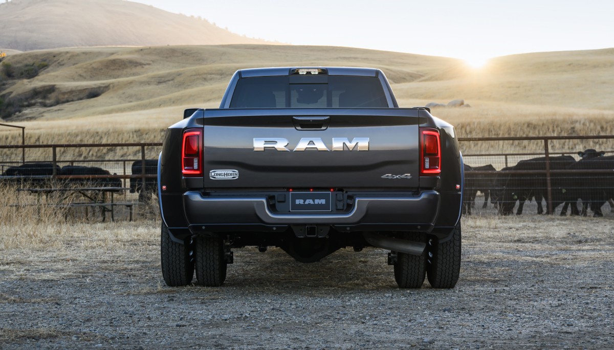 Se muestra el ángulo trasero de una Ram 3500 Limited Longhorn 4x4 Crew Cab 2026 negra estacionada en un rancho ganadero.