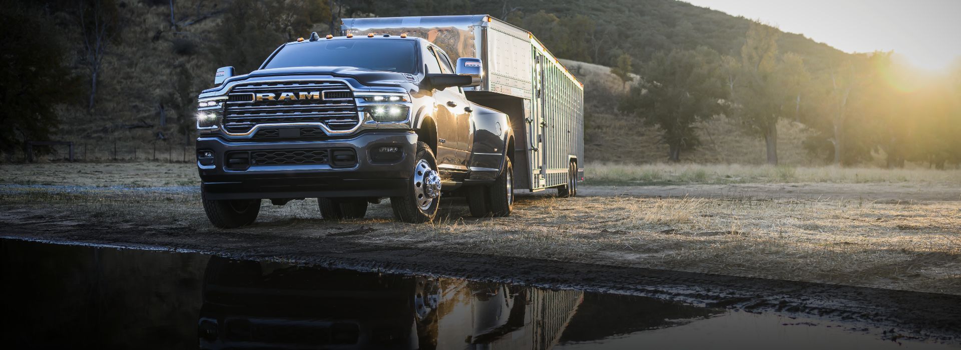 Una Ram 3500 Limited Longhorn 4x4 Crew Cab 2026 negra acarreando un remolque de quinta rueda grande para ganado fuera de la carretera, al lado de la costa.
