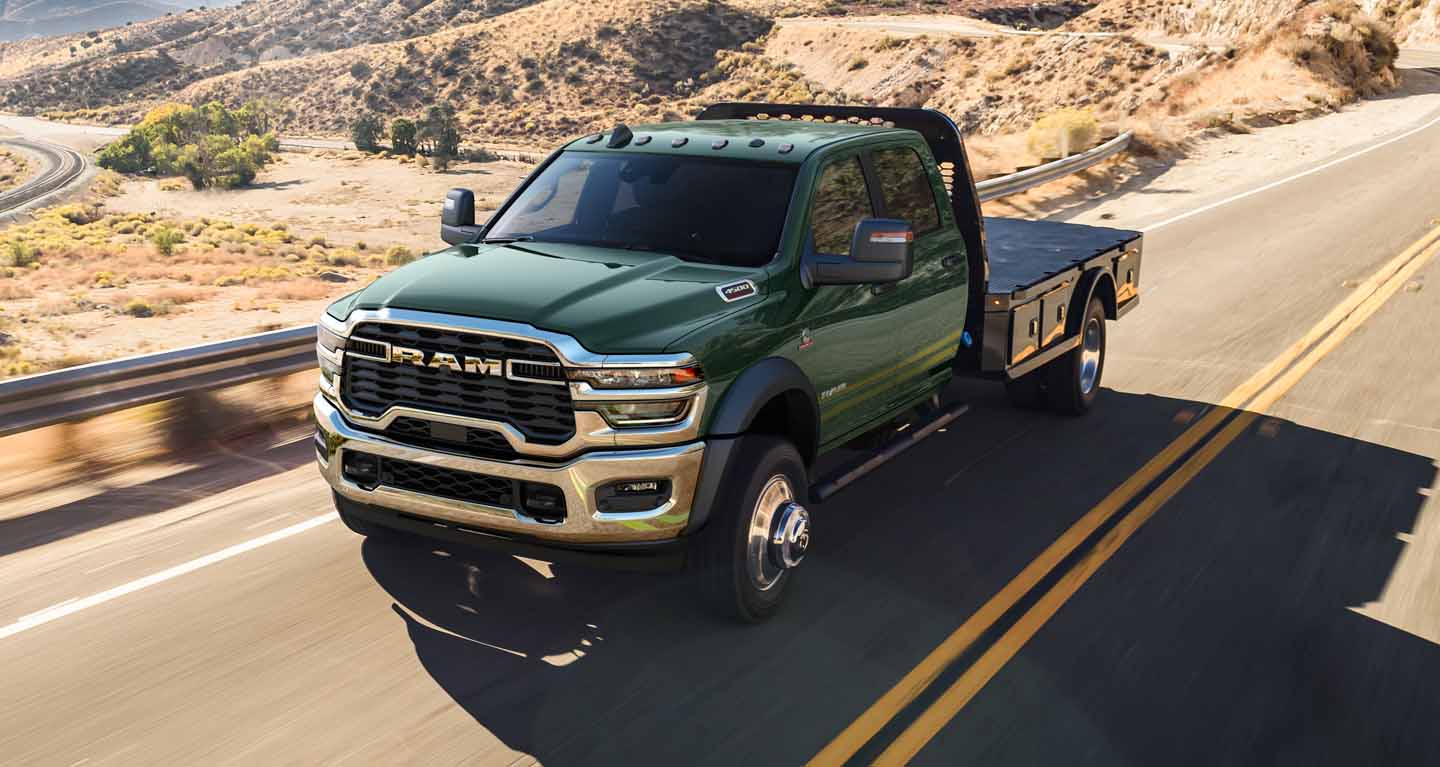 Se muestra Una Ram 4500 Big Horn 4x2 Chassis Cab Crew Cab 2026 verde, con caja tipo plataforma, avanza por una autopista.