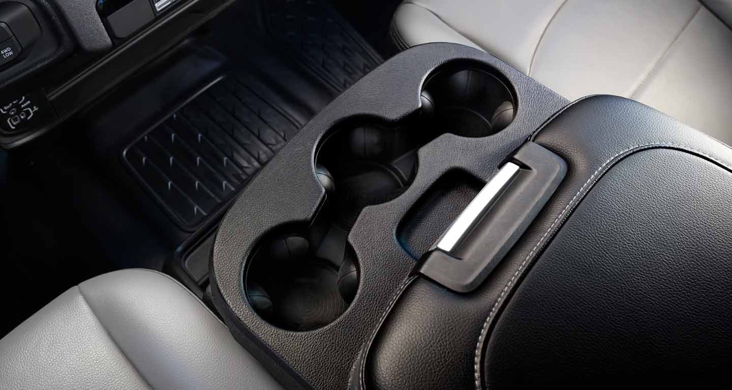 Se muestra La consola central reconfigurable en la Ram Chassis Cab 2026, con portavasos deslizantes, área de acople para smartphone y base de carga doble inalámbrica.