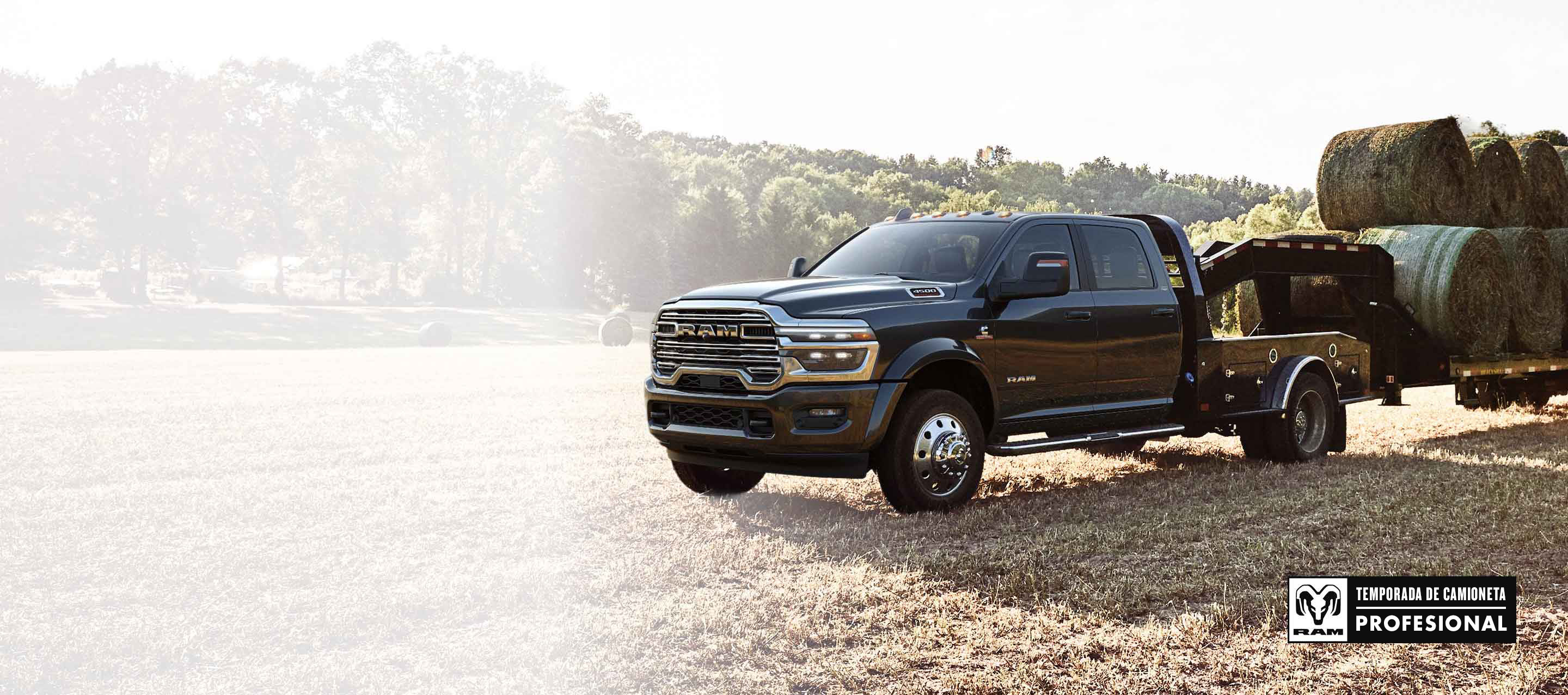 Una Ram 4500 Laramie Chassis Cab Crew Cab 2026 negra con un remolque tipo cuello de cisne cargada con varios fardos de heno, estacionada en un campo abierto. Temporada de camionetas Ram Professional.