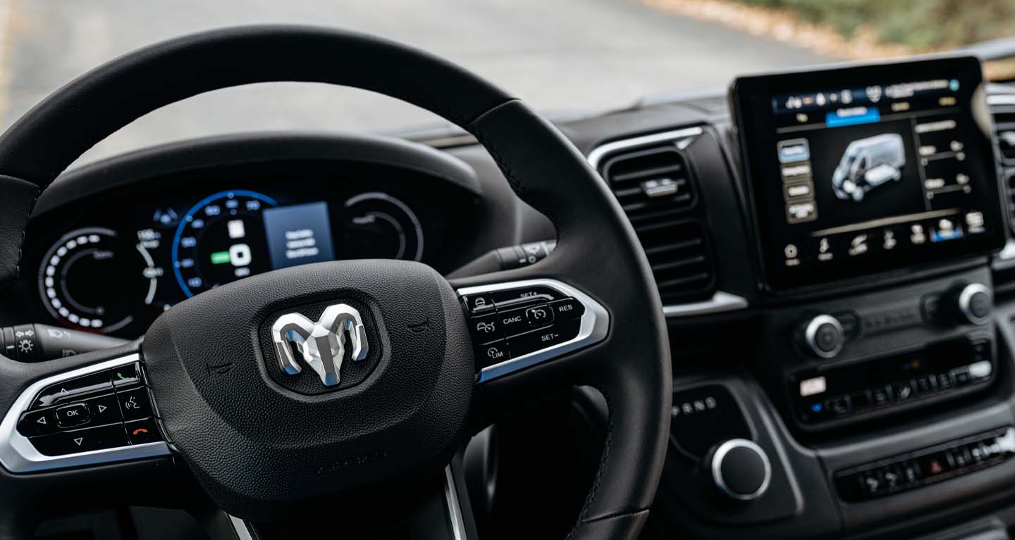 Mostrar El volante, la pantalla digital en el panel de instrumentos y la pantalla táctil de Uconnect en una Ram ProMaster EV 3500 Cargo Van 2026.