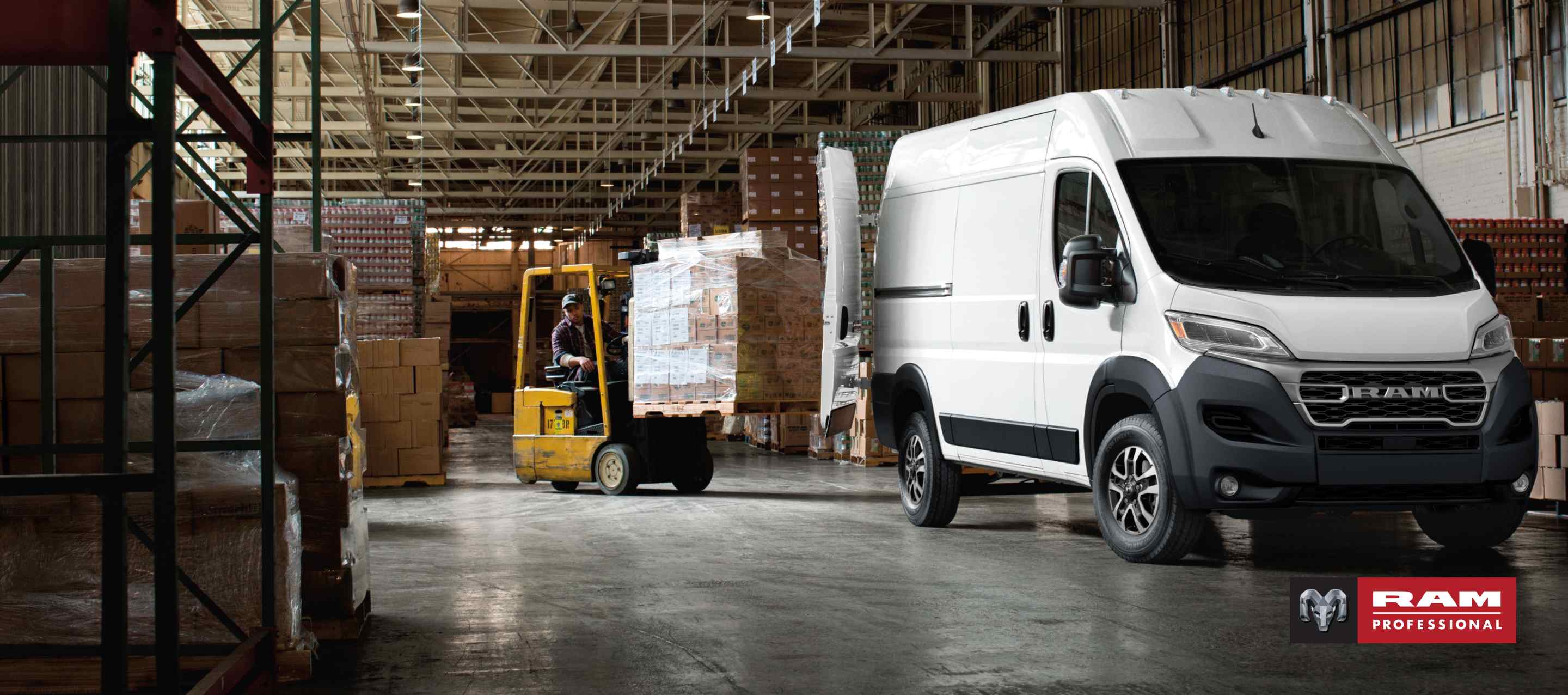 Un ángulo delantero del lado del pasajero de una Ram ProMaster 2500 SLT Cargo Van High Roof 2026 blanca estacionada en un depósito con las puertas traseras totalmente abiertas y un montacargas con una pila de cajas circulando hacia la parte trasera de la van. Ram Professional.