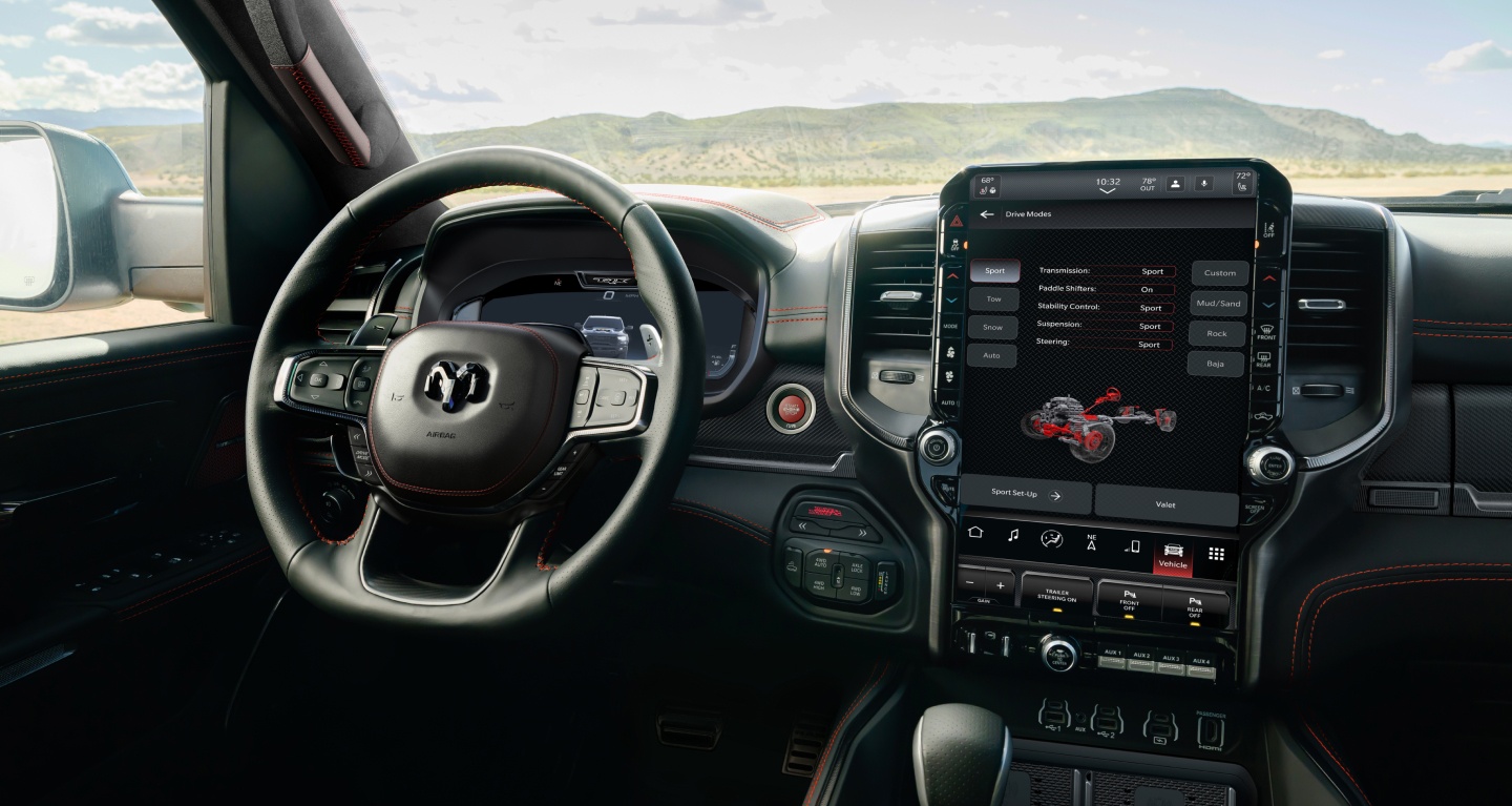 Se muestra el interior de la Ram 1500 TRX SRT 2027, con foco en el volante, el panel de instrumentos digital, la pantalla táctil Uconnect y los controles de la consola central, con la página del Modo de manejo deportivo en la pantalla táctil.