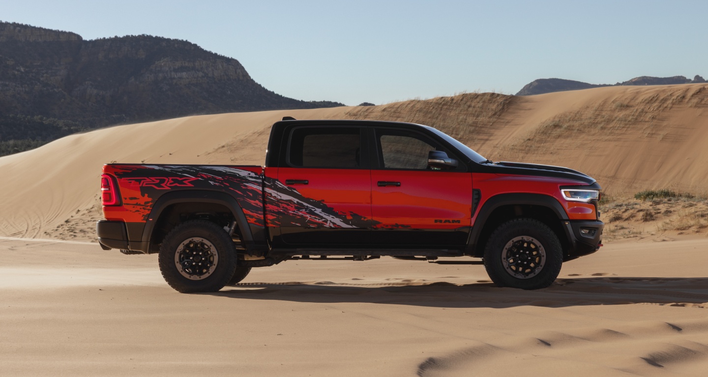 Se muestra una Ram 1500 TRX SRT Bloodshot Night Edition 2027 roja con capó y techo negros y gráficos especiales de salpicaduras en el lateral.