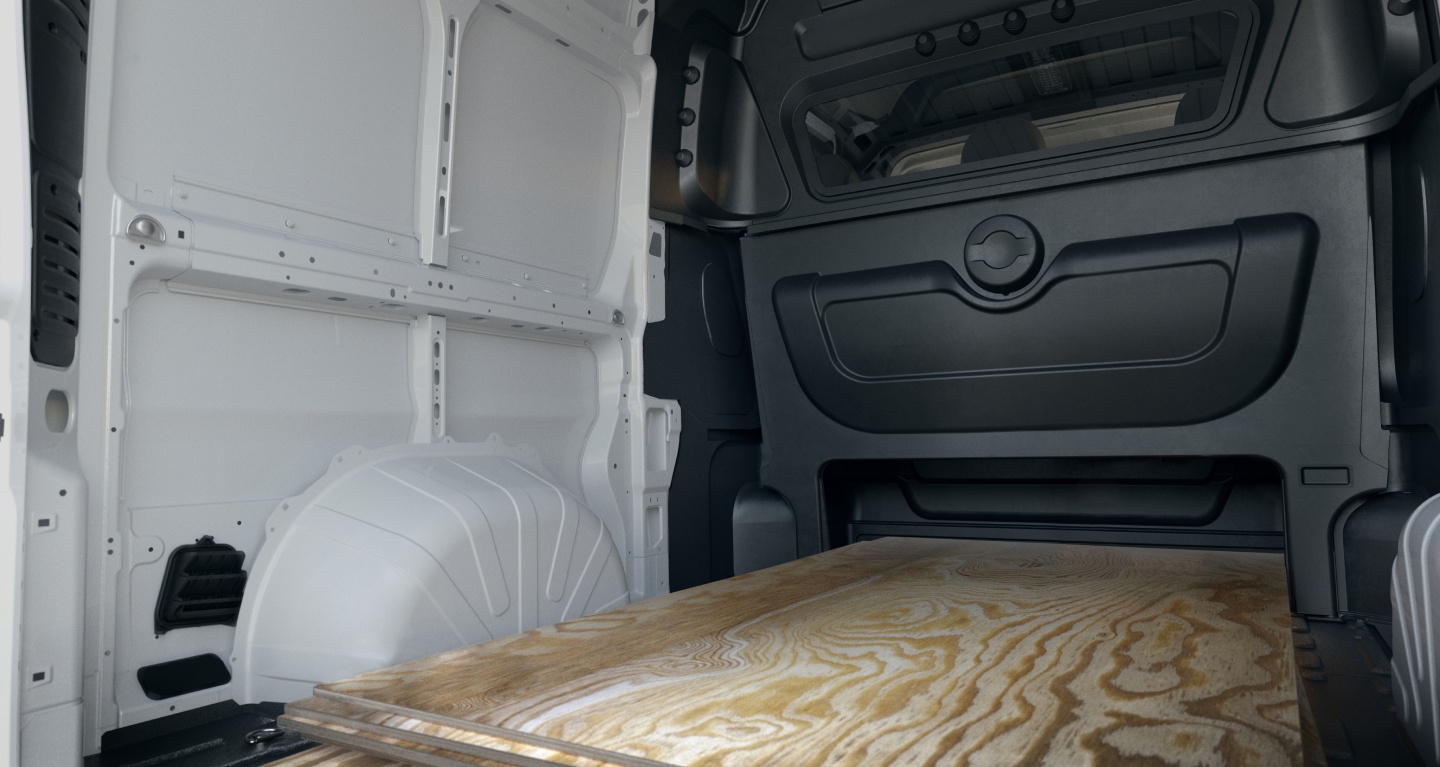 Display The rear of the 2027 Ram ProMaster Cargo Van High Roof with the Crew Van Package, displaying the large cargo area, the partition between the rear seats and cargo area and the six inches of extra height under the rear seat.