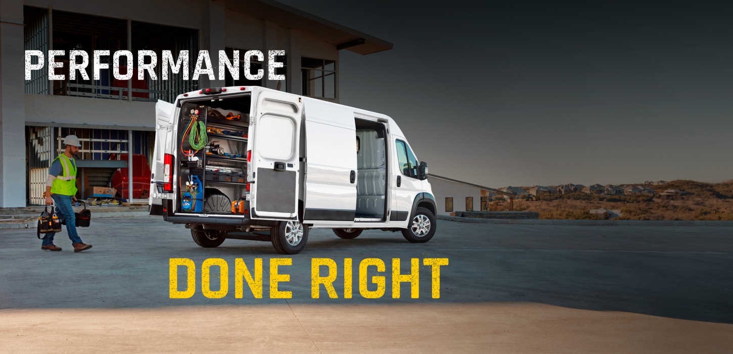 La parte trasera de una Ram ProMaster 2500 SLT High Roof Cargo Van 2027 blanca con la puerta deslizable del lado del pasajero y las puertas traseras abiertas por las cuales se observan estantes llenos de herramientas y un técnico caminando hacia la van. Performance Done Right.