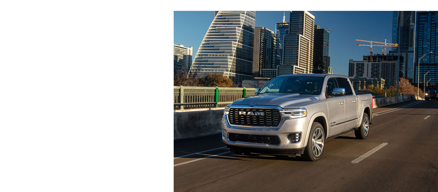Una Ram Tungsten Crew Cab 2025 plateada cruza un puente en el distrito financiero del centro de una ciudad.