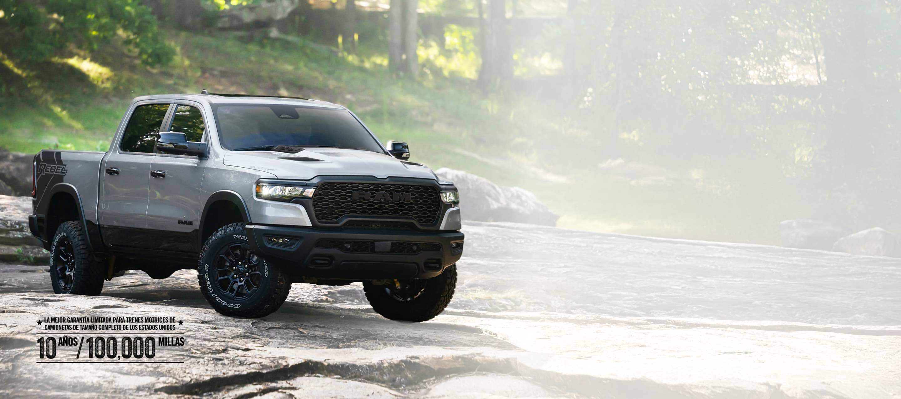 Una Ram 1500 Rebel 4x4 Crew Cab 2026 plateada recorriendo un sendero irregular fuera de carretera. La mejor garantía limitada del tren motriz para camionetas de tamaño completo de los Estados Unidos, de 10 años/100,000 millas.