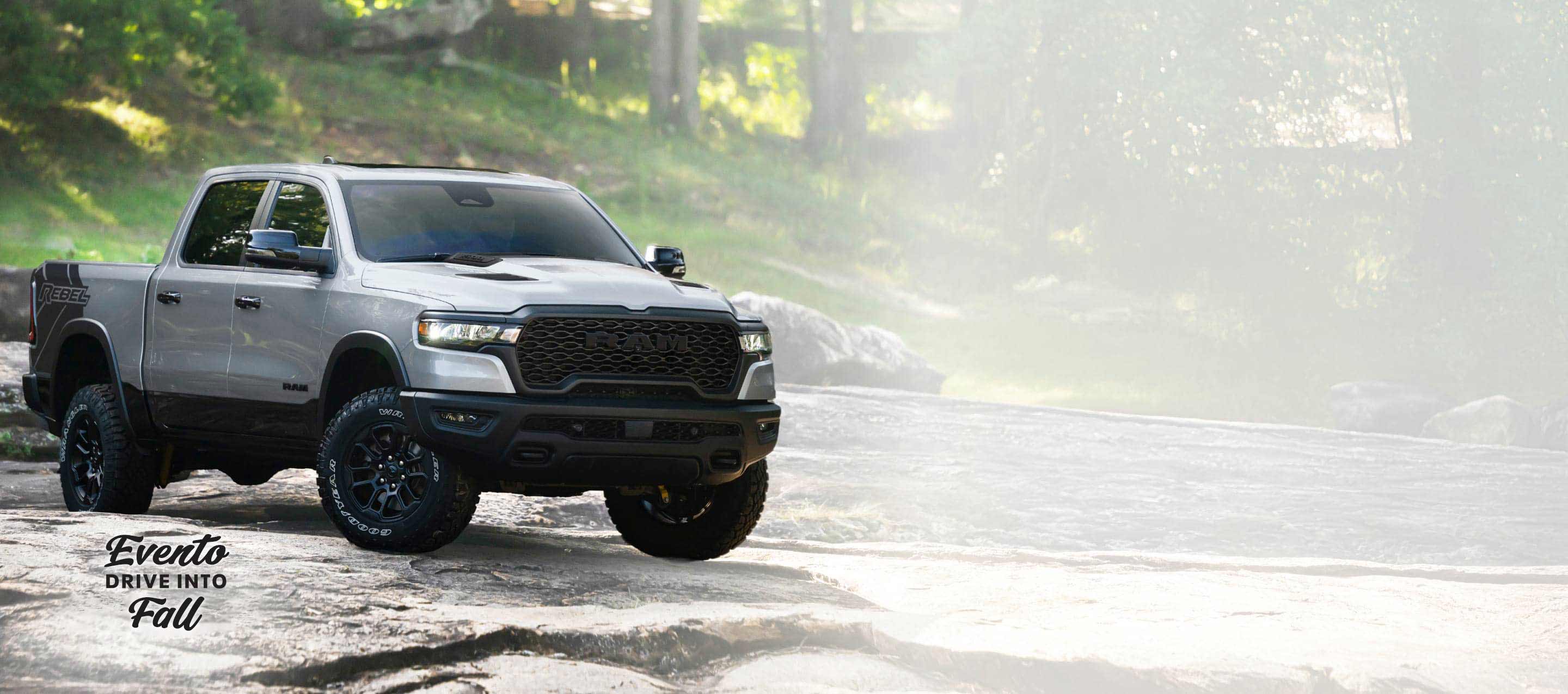 Una Ram 1500 Rebel 4x4 Crew Cab 2026 plateada recorriendo un sendero irregular fuera de carretera. Evento de ventas Drive Into Fall.