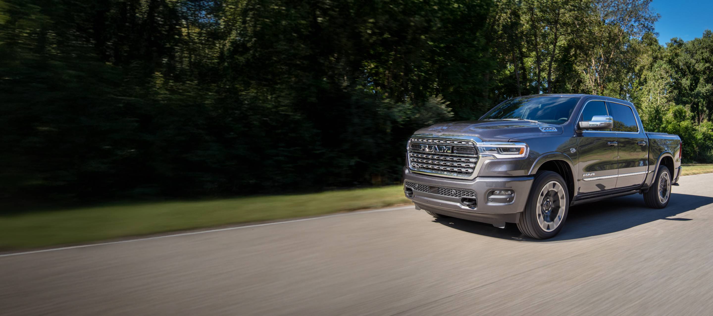 Una Ram 1500 Limited 4x4 Crew Cab 2026 gris circulando por un camino campestre. Evento de ventas Drive Into Fall y garantía del tren motriz.