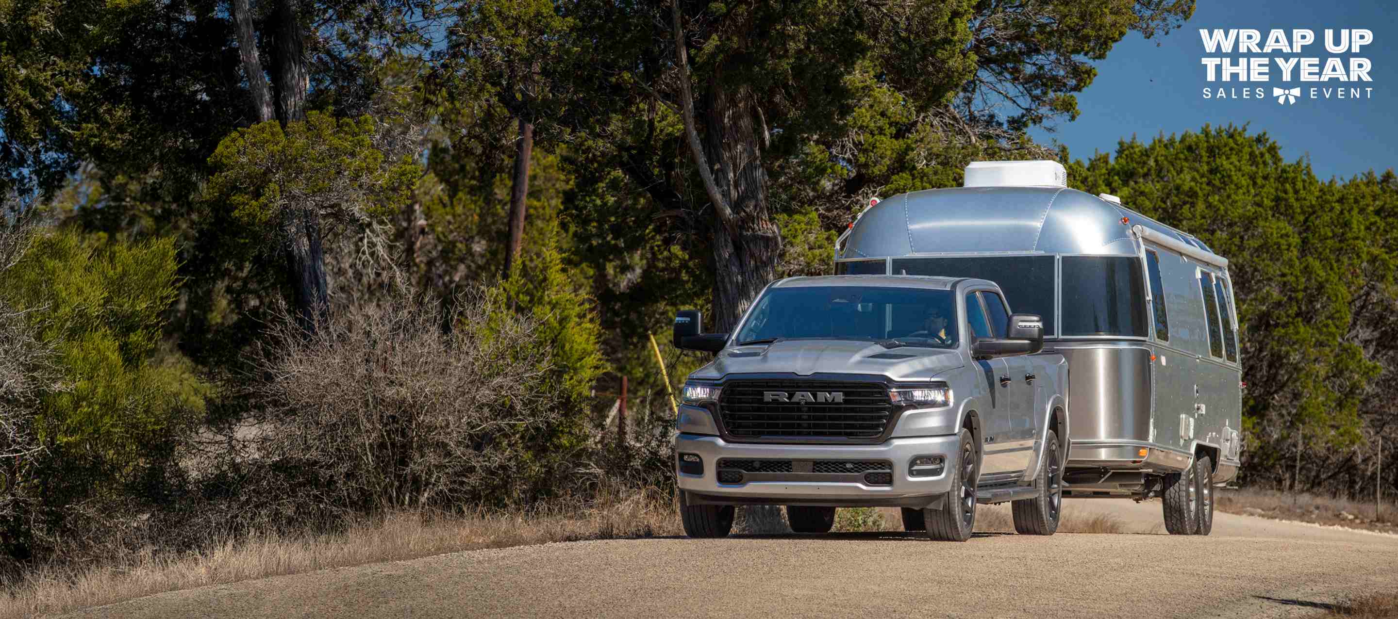 Una Ram 1500 Laramie Crew Cab 2025 llevando un remolque grande y circulando por una autopista. El evento de ventas Fin de año.